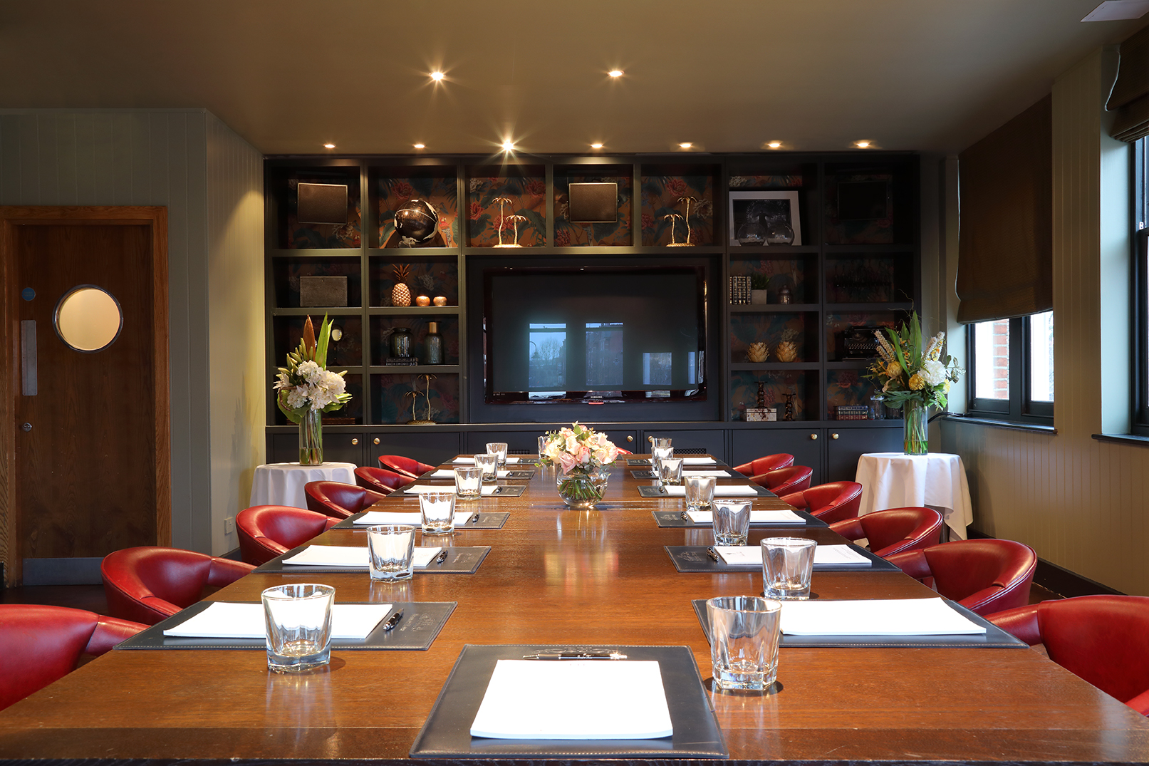 Private dining room with wooden table and red chairs for corporate meetings and events.