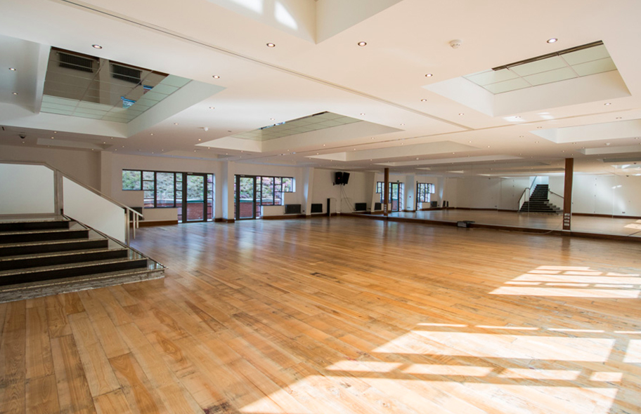 Spacious event venue with polished floors and natural light for workshops and gatherings.