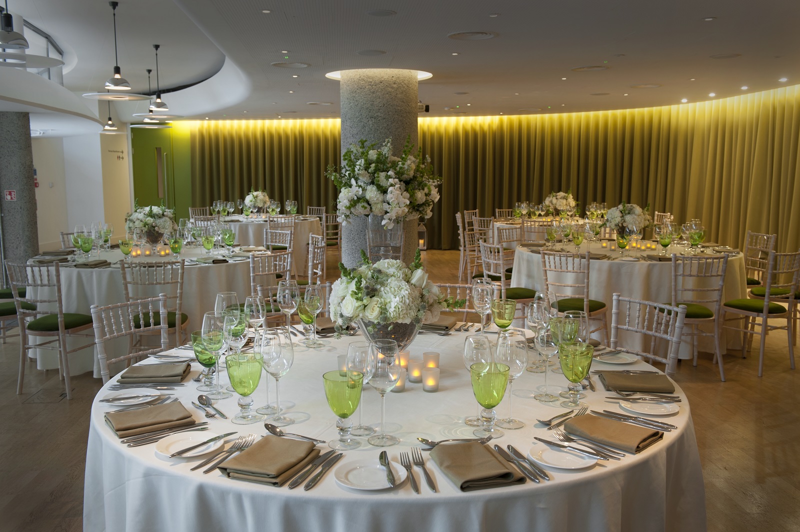 Elegant event space in Terrace Gallery, London with round tables and floral centerpieces.