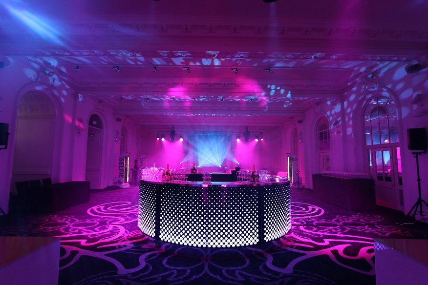 Stylish event space with modern bar and vibrant lighting for networking or celebrations.