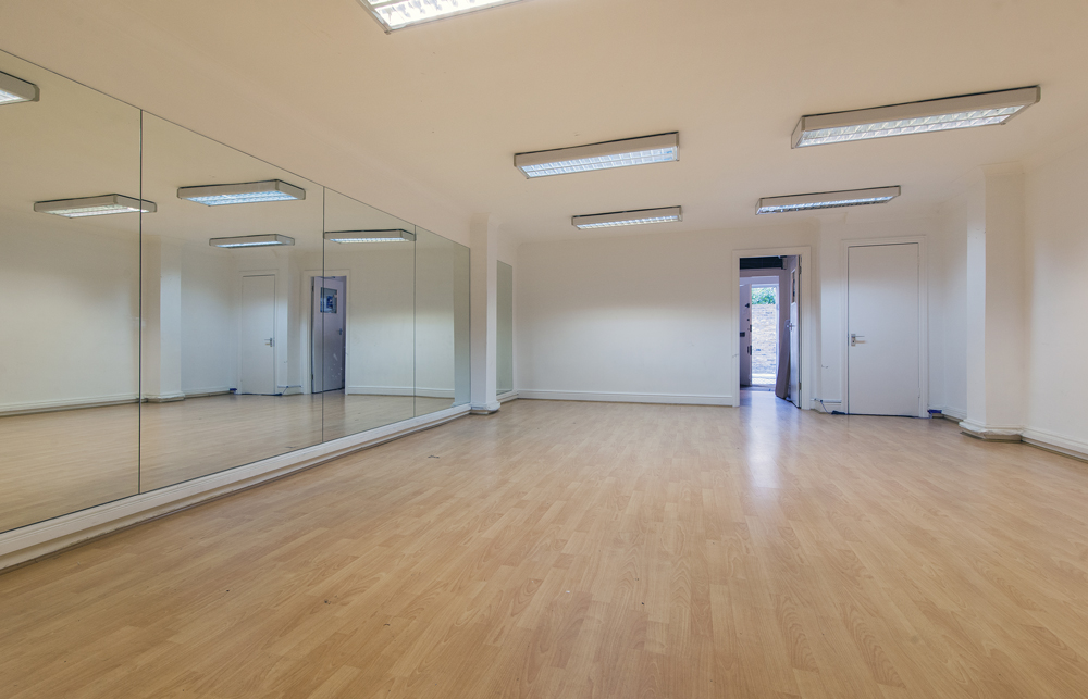 Versatile meeting space with hardwood floors, ideal for workshops and fitness classes.