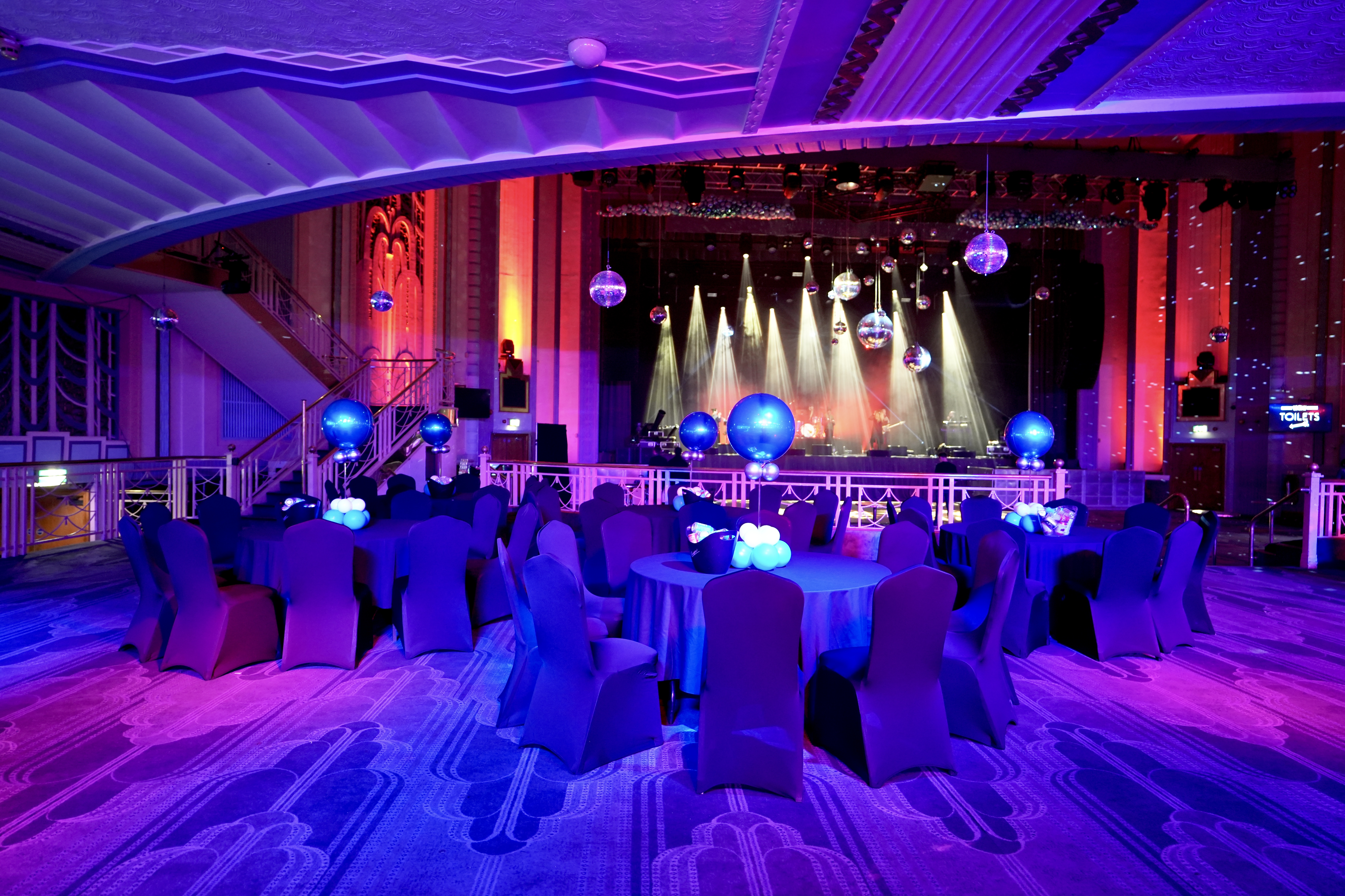 Christmas party gala at Troxy with elegant blue tables and dynamic stage lighting. - Banner