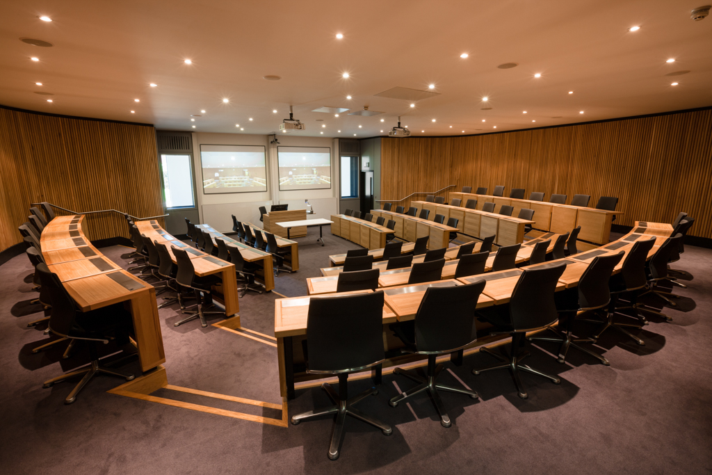 Modern lecture theatre with tiered seating and dual screens at Saïd Business School, Oxford.