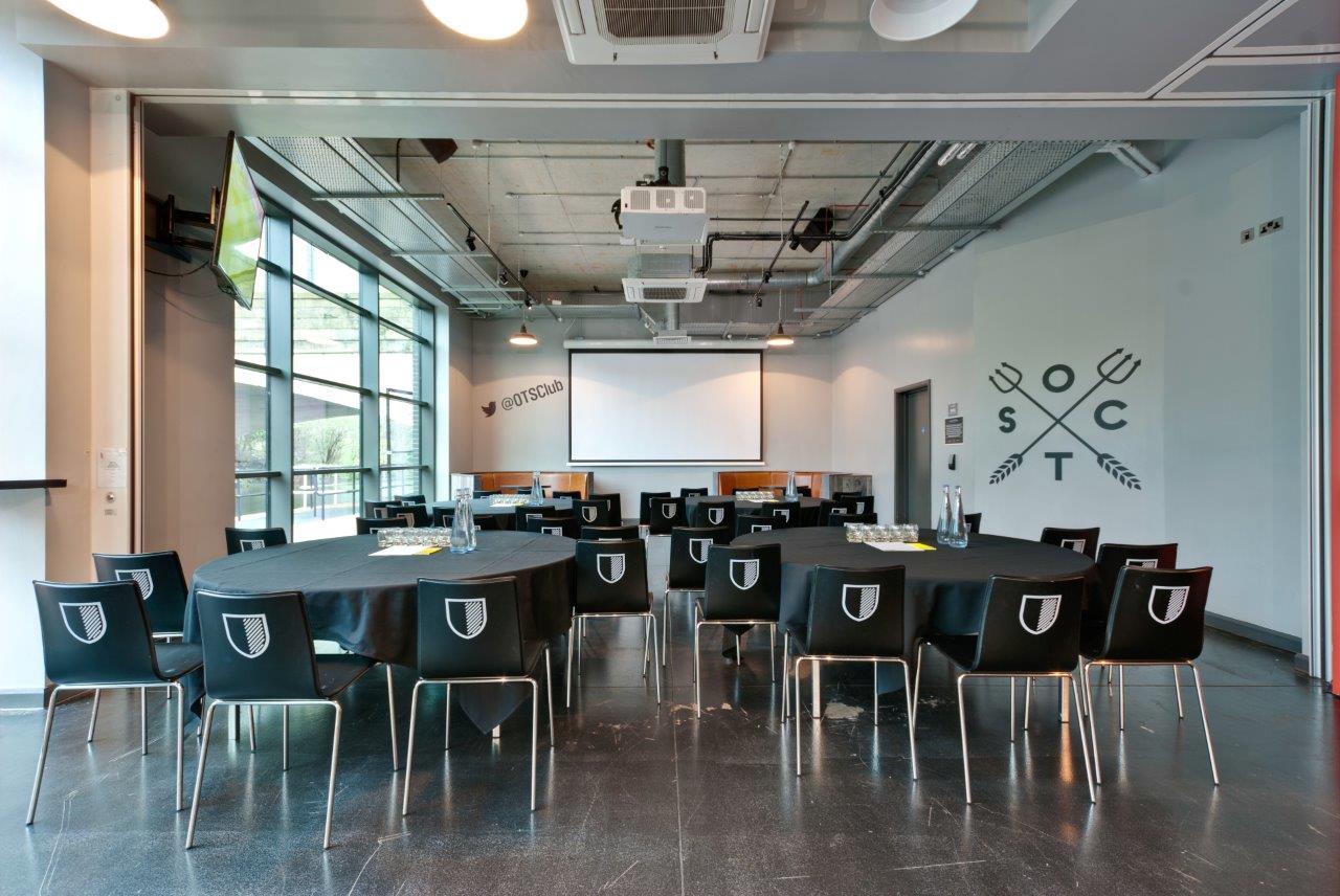 Old Trafford Supporters Club event space with round tables for meetings and workshops.