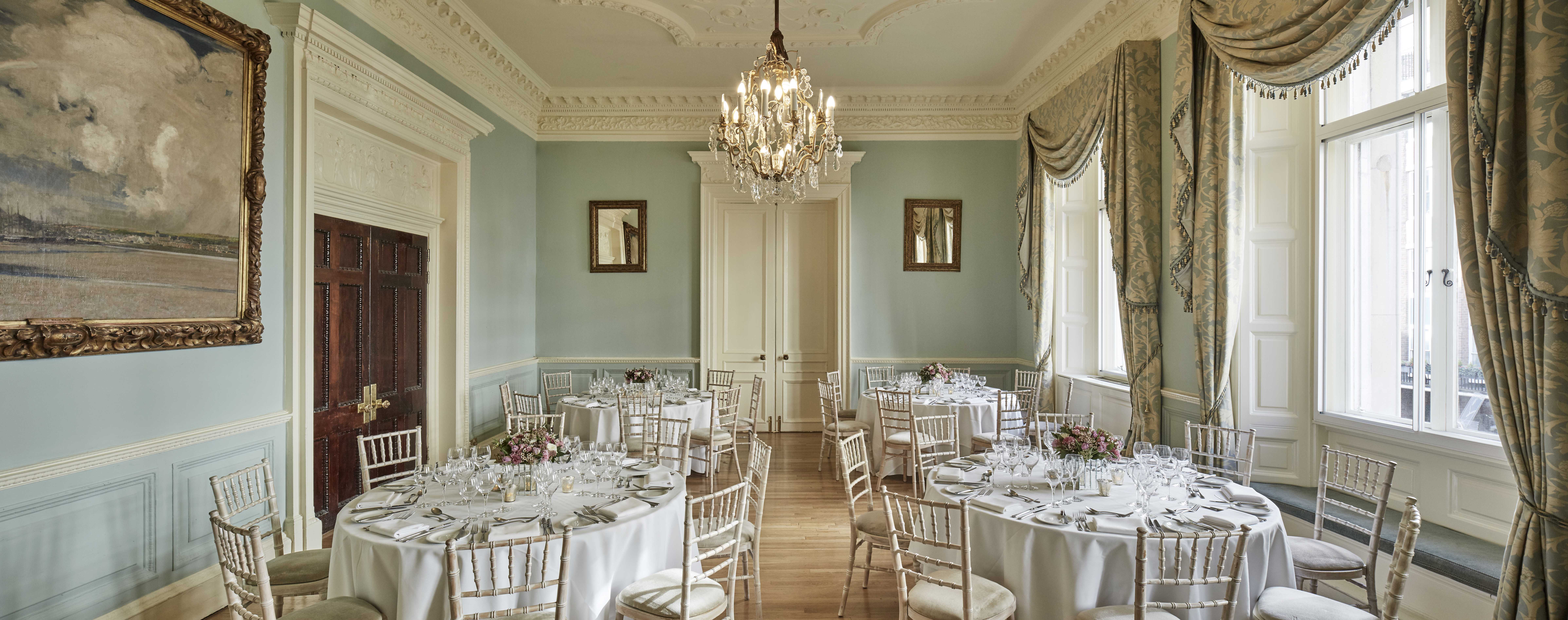 Elegant banquet room in Dartmouth House, featuring round tables and a glamorous chandelier.