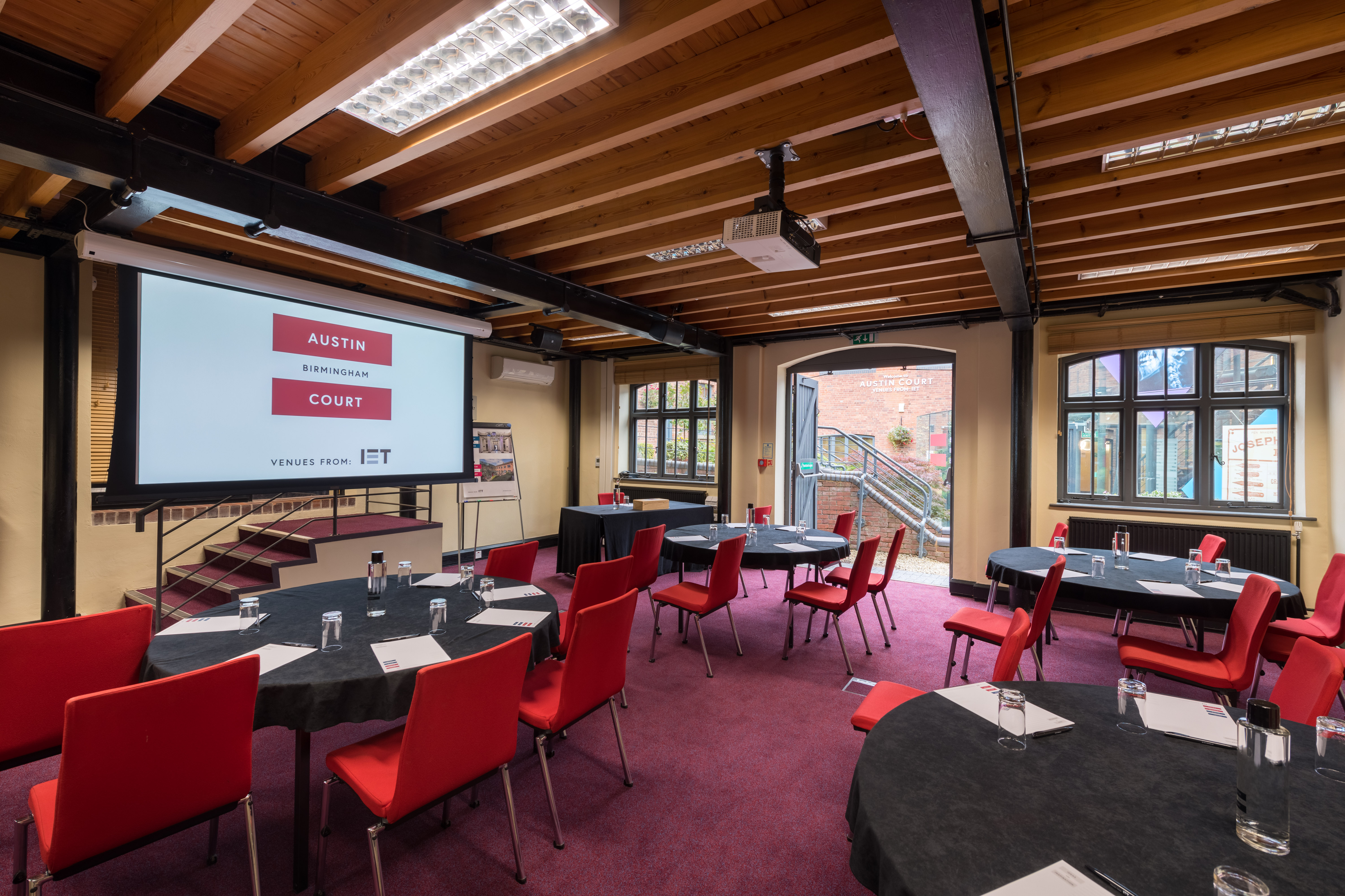 Boulton Room at IET Birmingham: Austin Court, featuring round tables and red chairs for meetings.