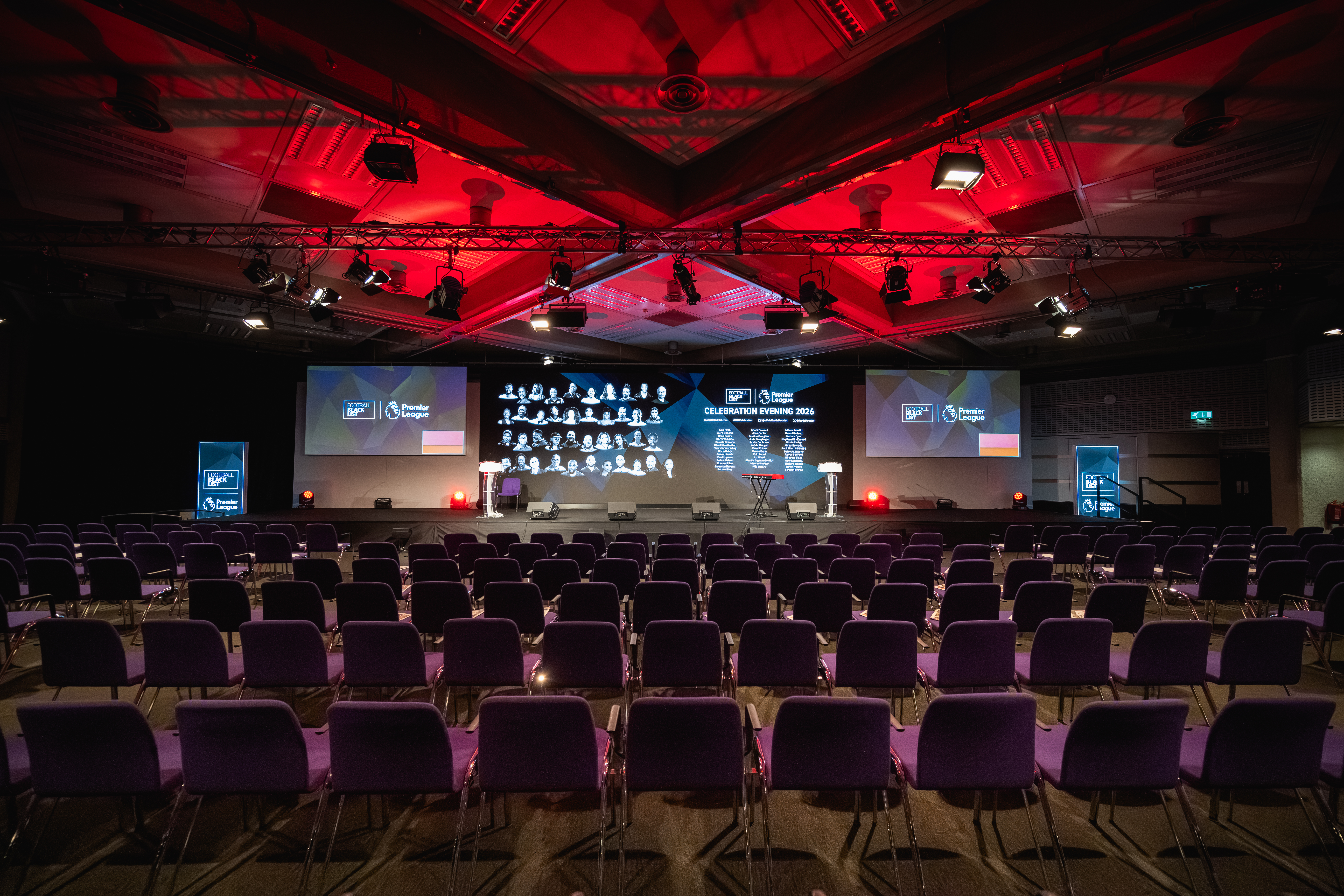 Theater-style QEII Centre room with LED screen and red lighting for corporate awards or keynotes.