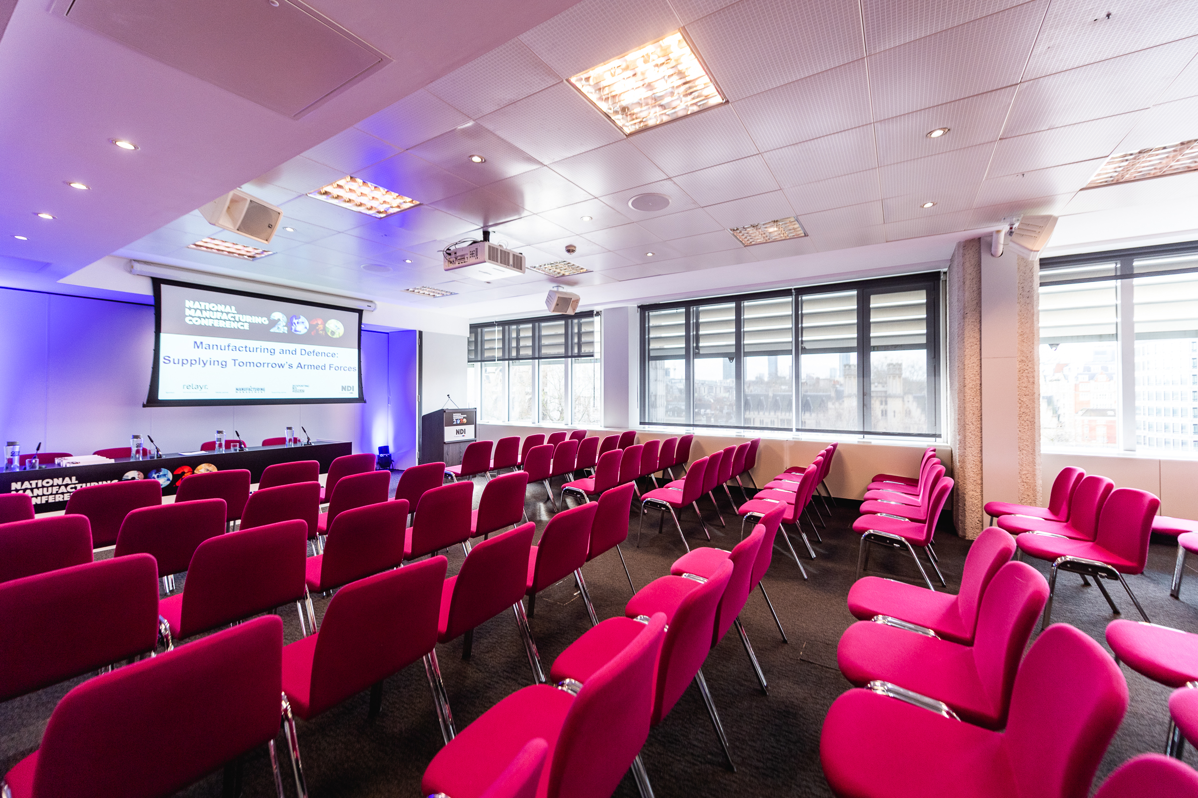 Modern conference room with pink chairs for events at QEII Centre, bright and inviting.
