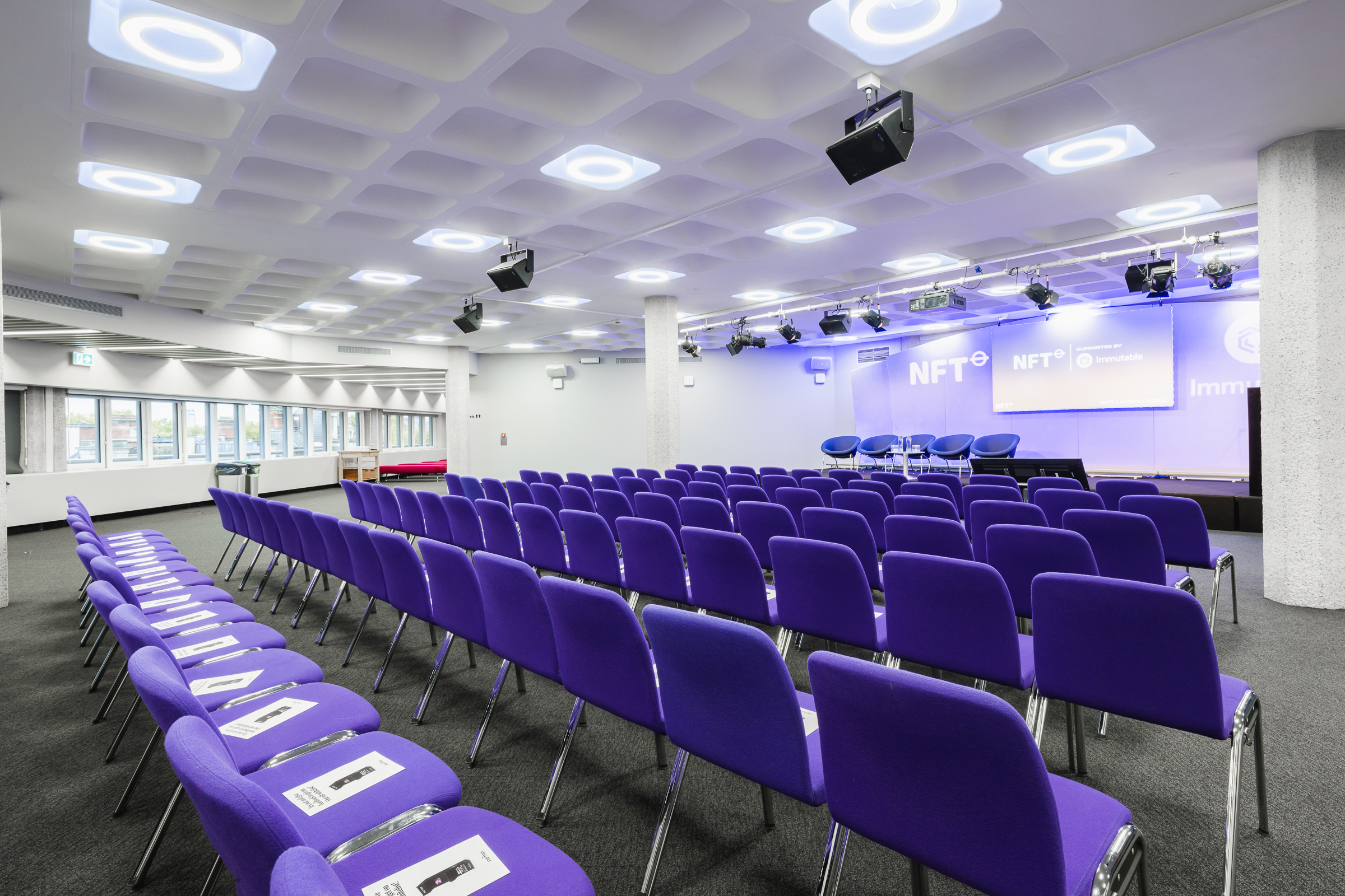 Modern conference room in QEII Centre with purple chairs for events and presentations.