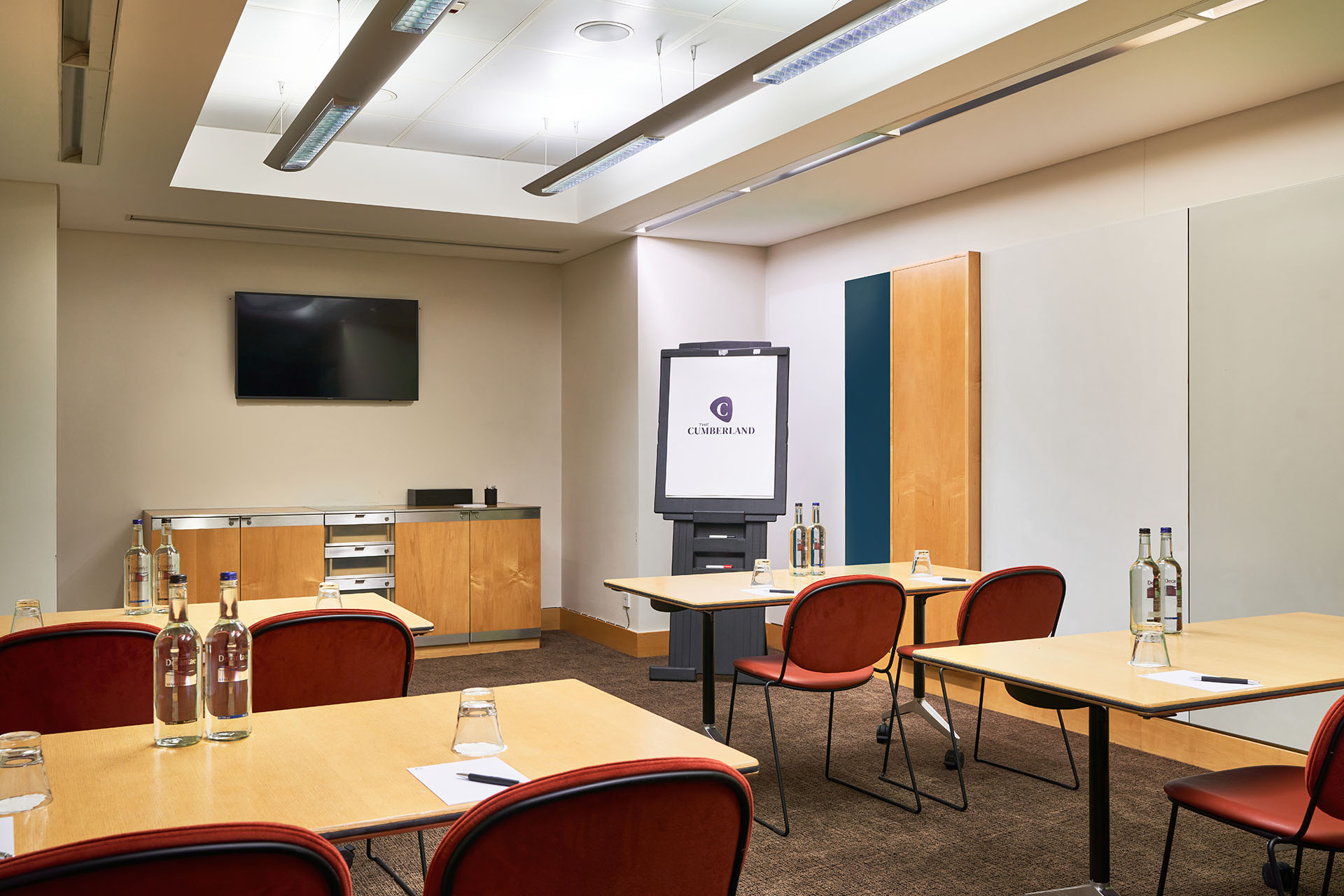Modern meeting room in The Cumberland Hotel with natural light and presentation screen.