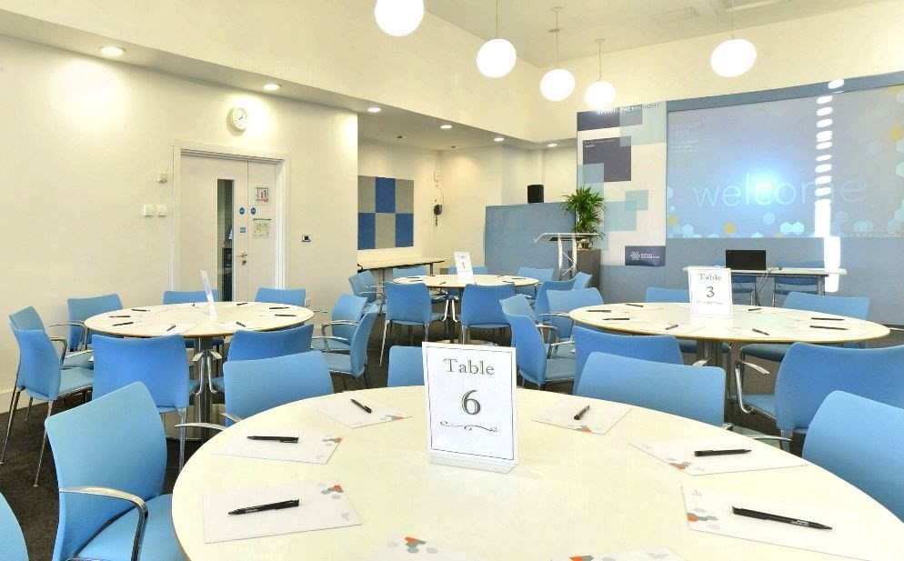 Modern Vygotsky Suite meeting room with round tables, ideal for workshops and events.