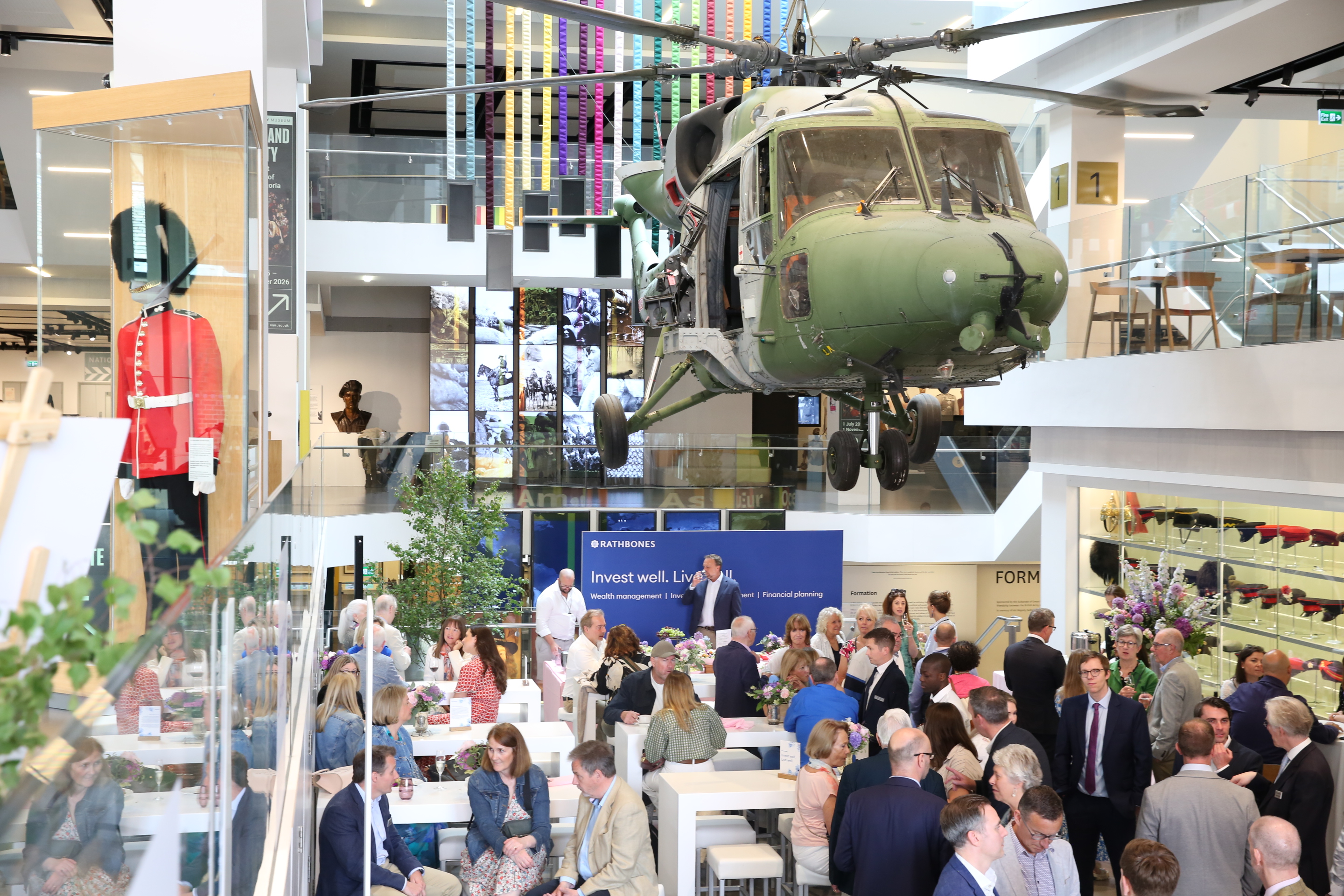 Corporate networking event in National Army Museum atrium with suspended helicopter focal point.