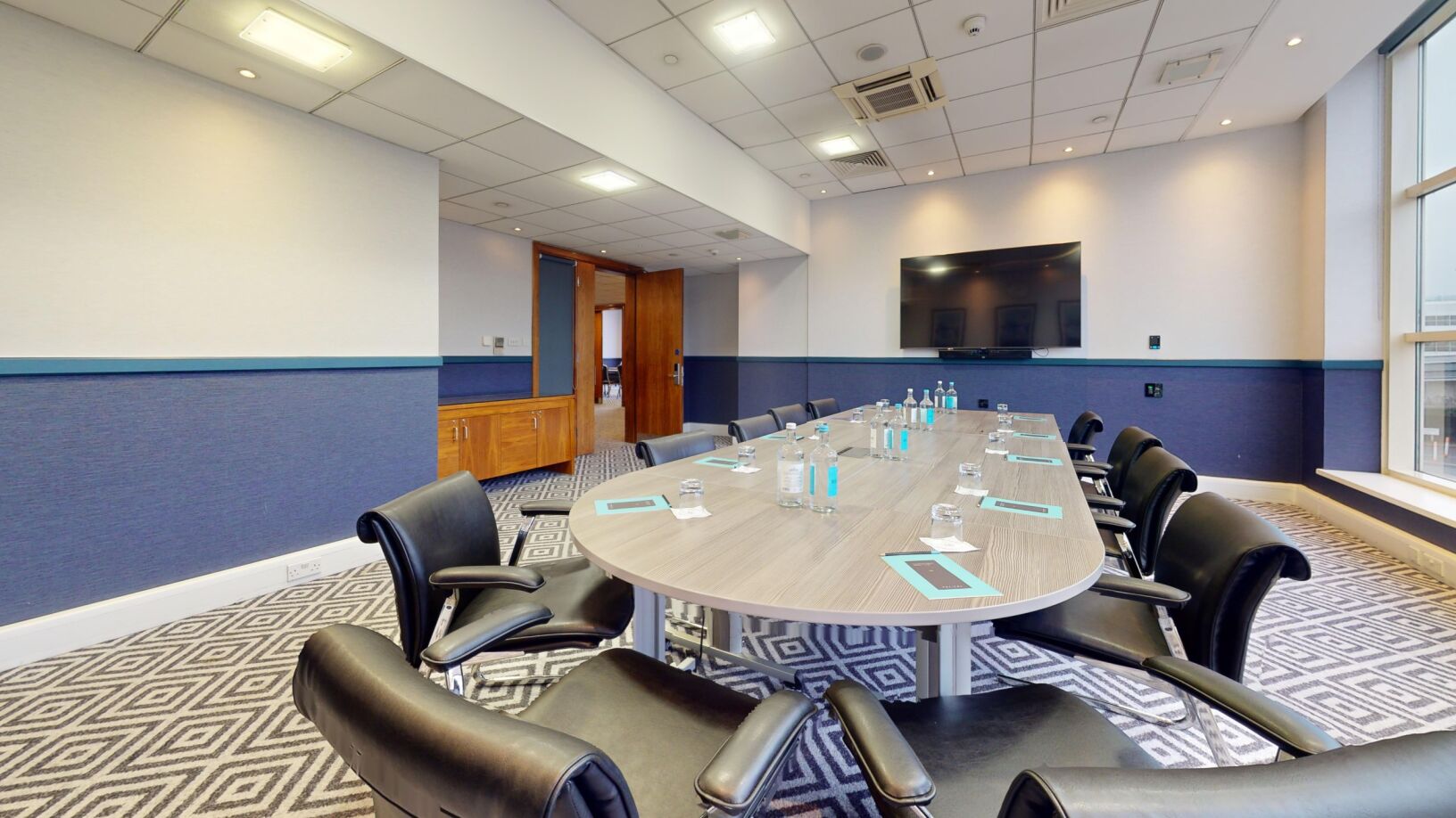 Meeting room at Sofitel London Gatwick with oval table and large screen for events.
