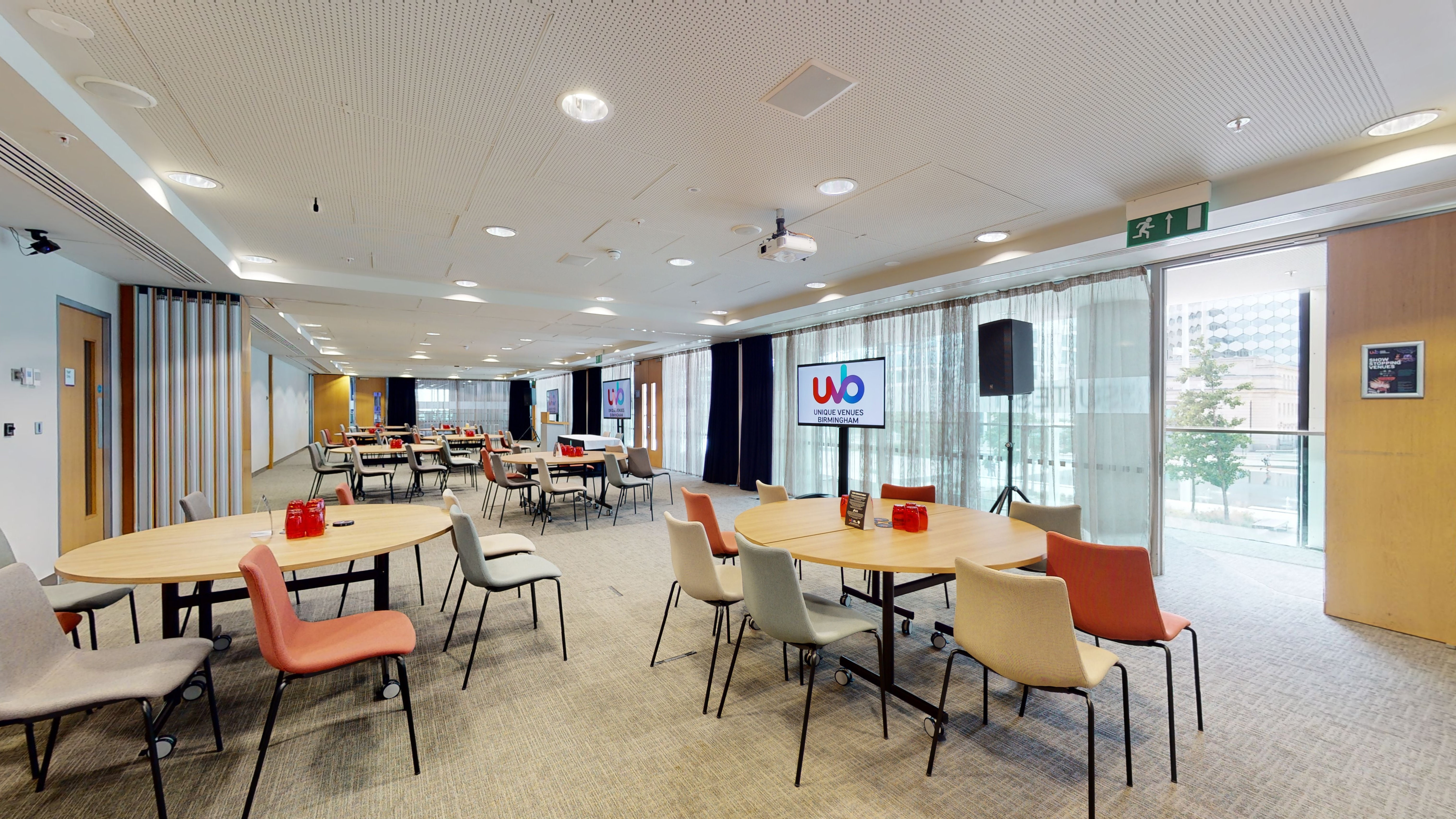 Versatile meeting room with round tables, ideal for workshops and networking events.