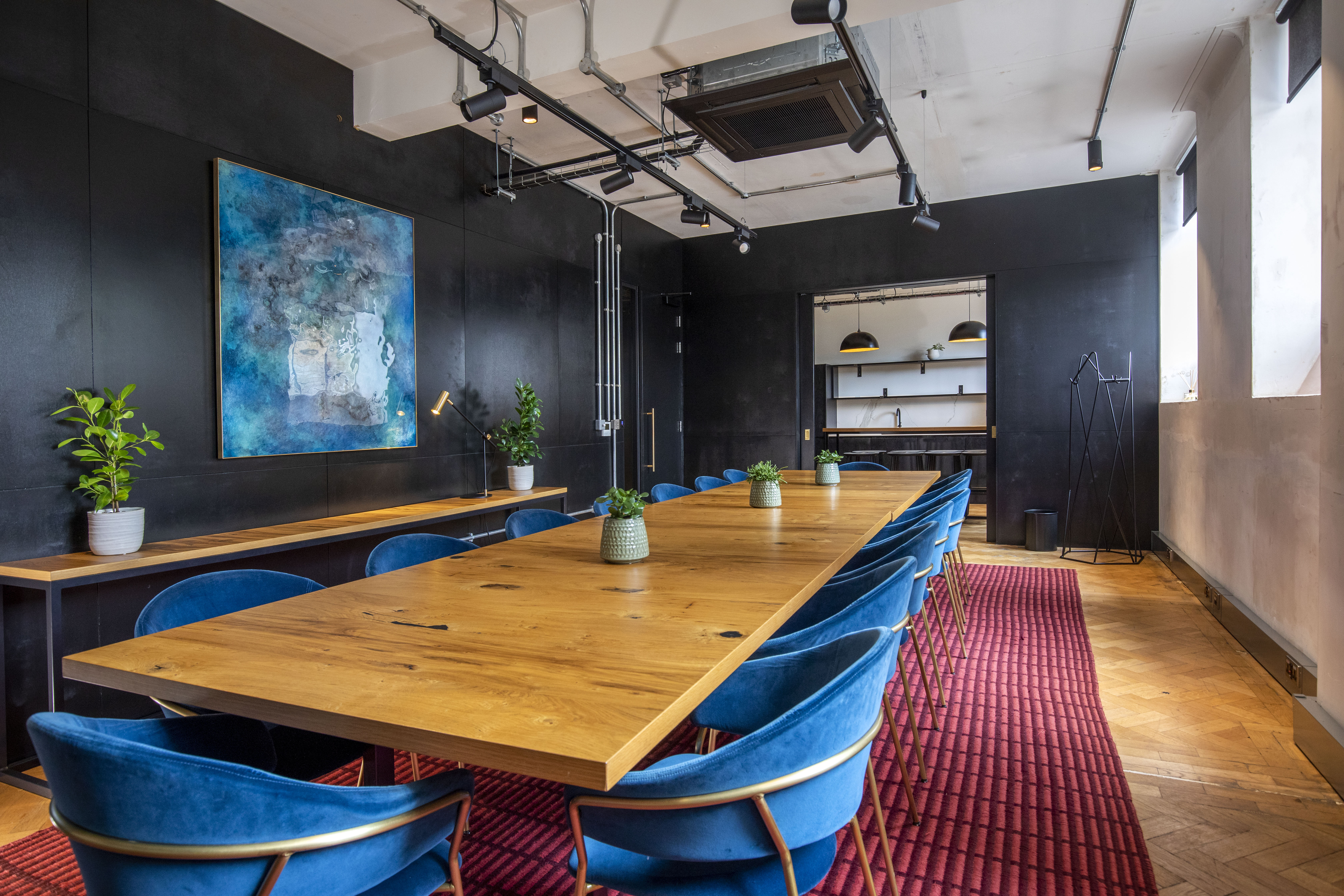 Modern boardroom with black walls and blue velvet chairs for creative meetings and executive events.