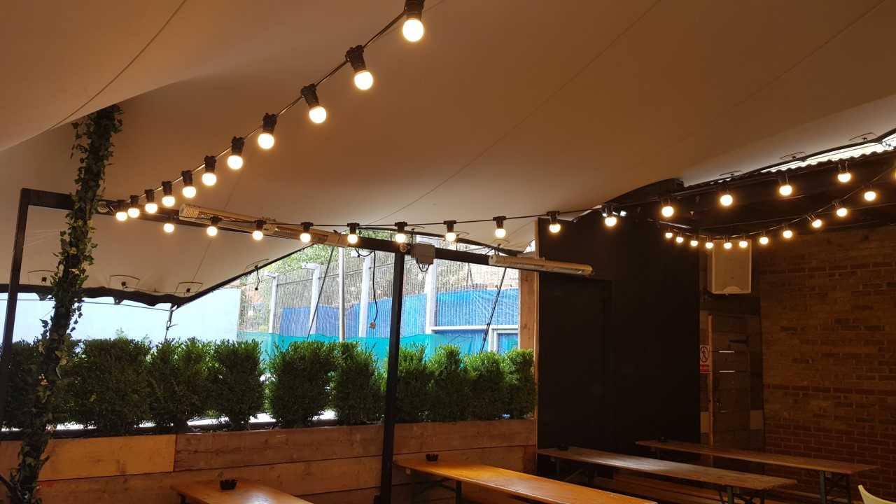 Outdoor event space at Bermondsey Bar & Kitchen with string lights and greenery.