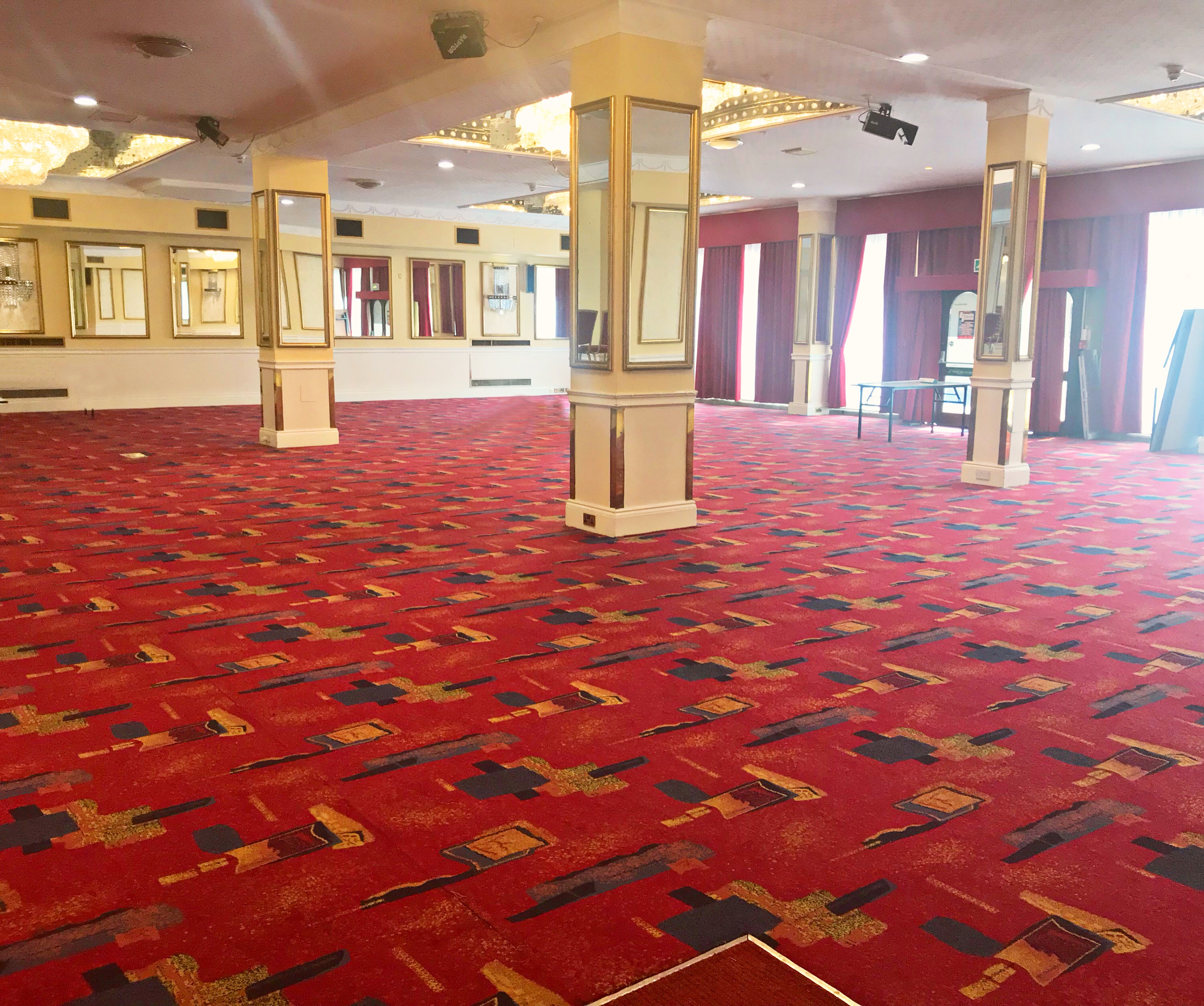 Spacious event venue with red carpet and natural light at Britannia Sachas Hotel.