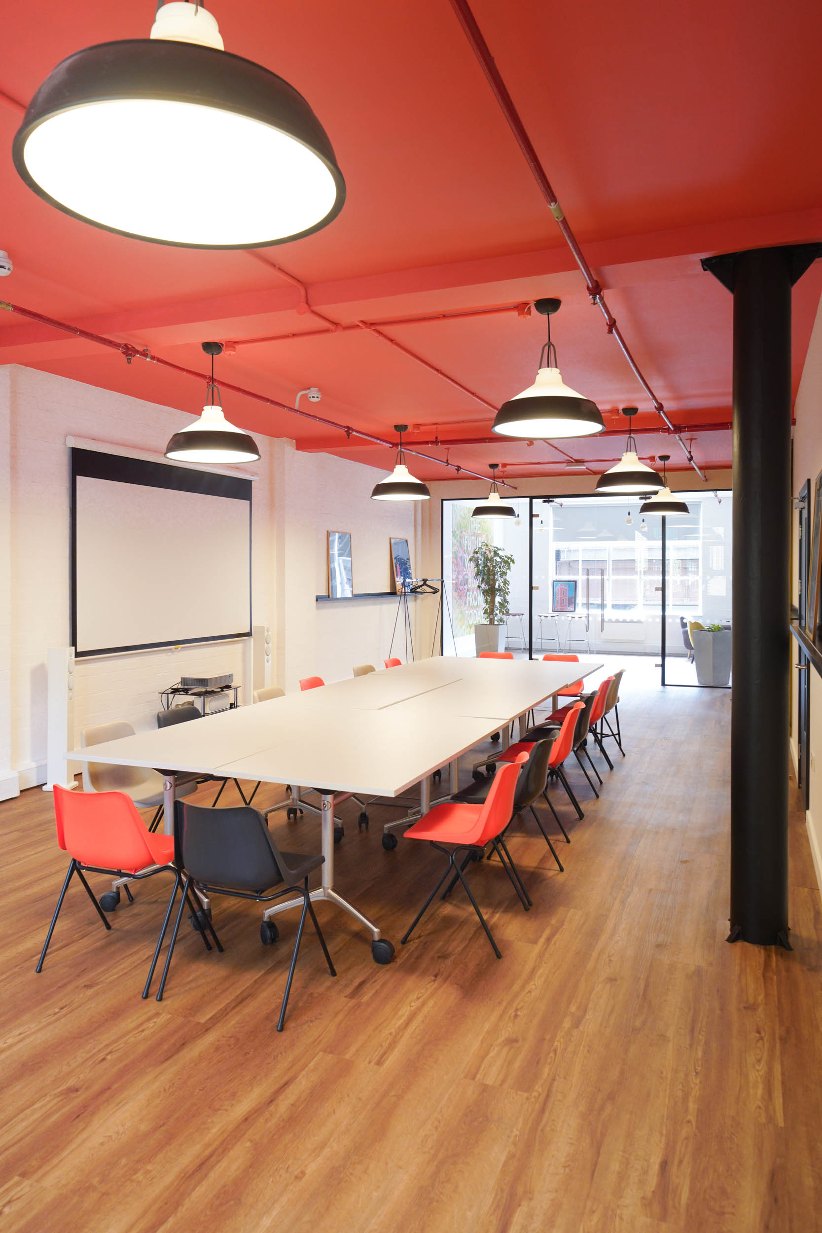Modern meeting room at The Hive, London Bridge, with colorful chairs and projector screen.