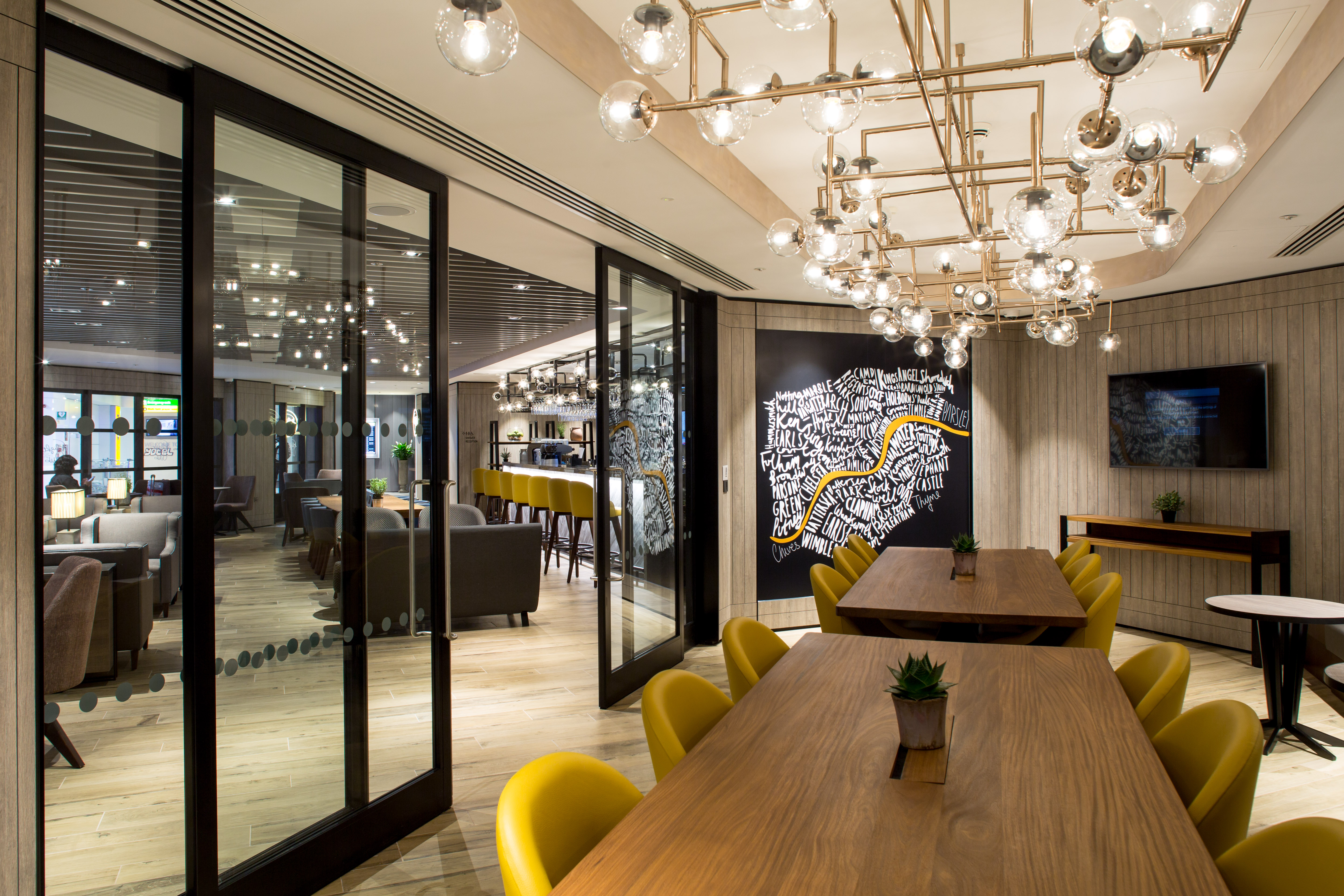 Modern meeting room with wooden table and yellow chairs for collaborative events. - Banner