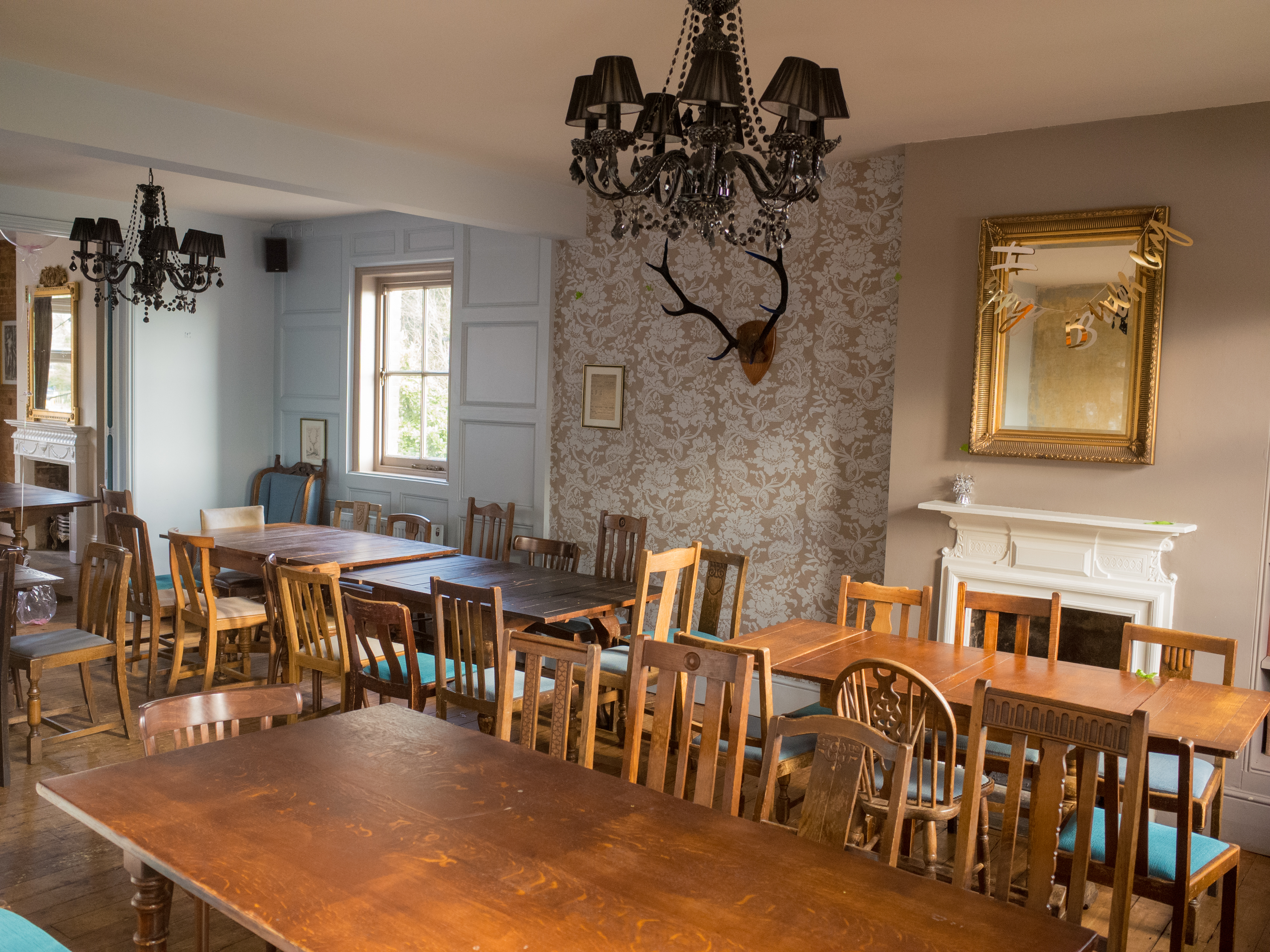 Charming event space at Adam & Eve with wooden tables and elegant chandeliers.