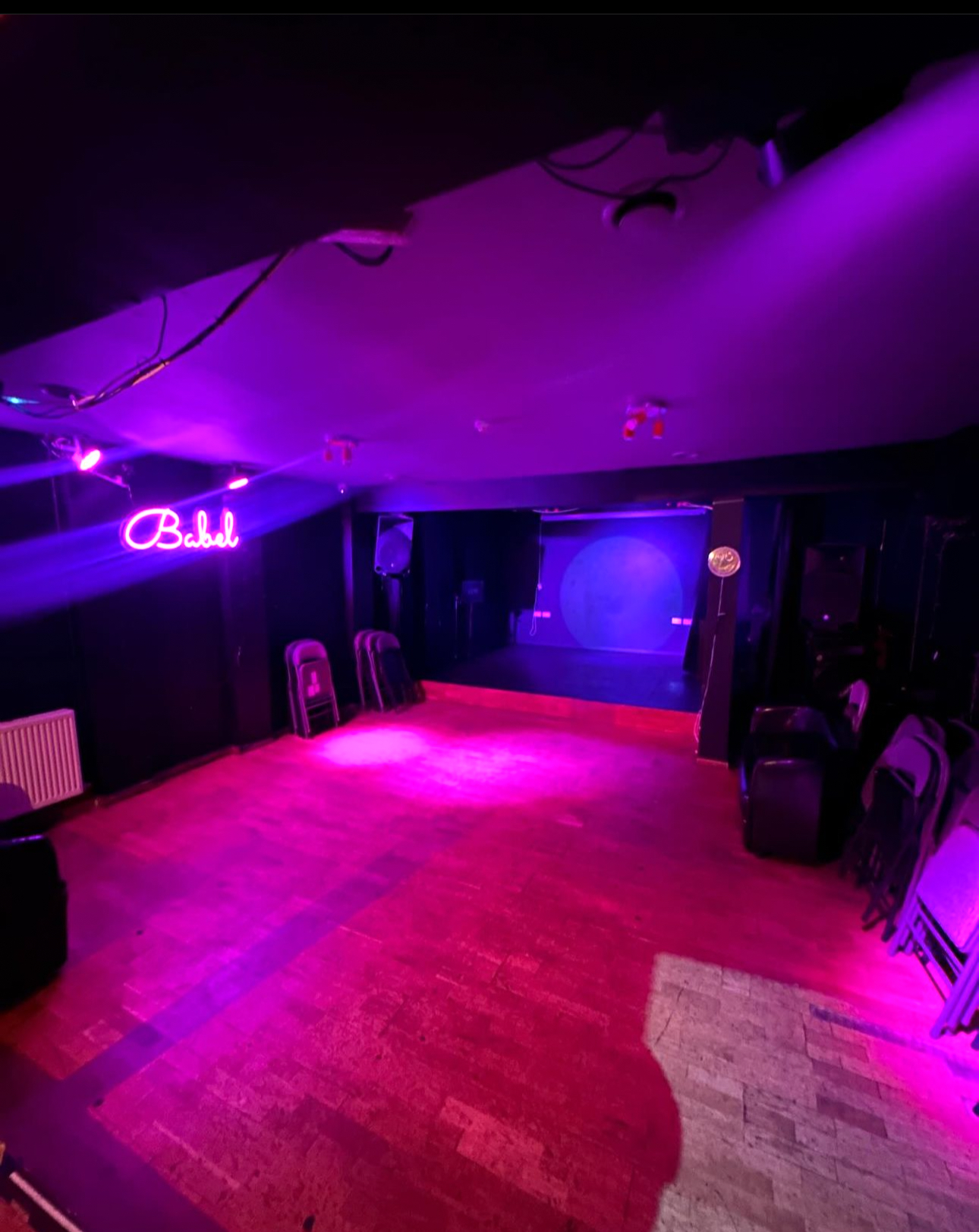 Versatile event space at Babel Art House with vibrant purple lighting for performances.