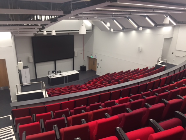 Modern auditorium with tiered red seating for conferences and workshops in Cambridge.
