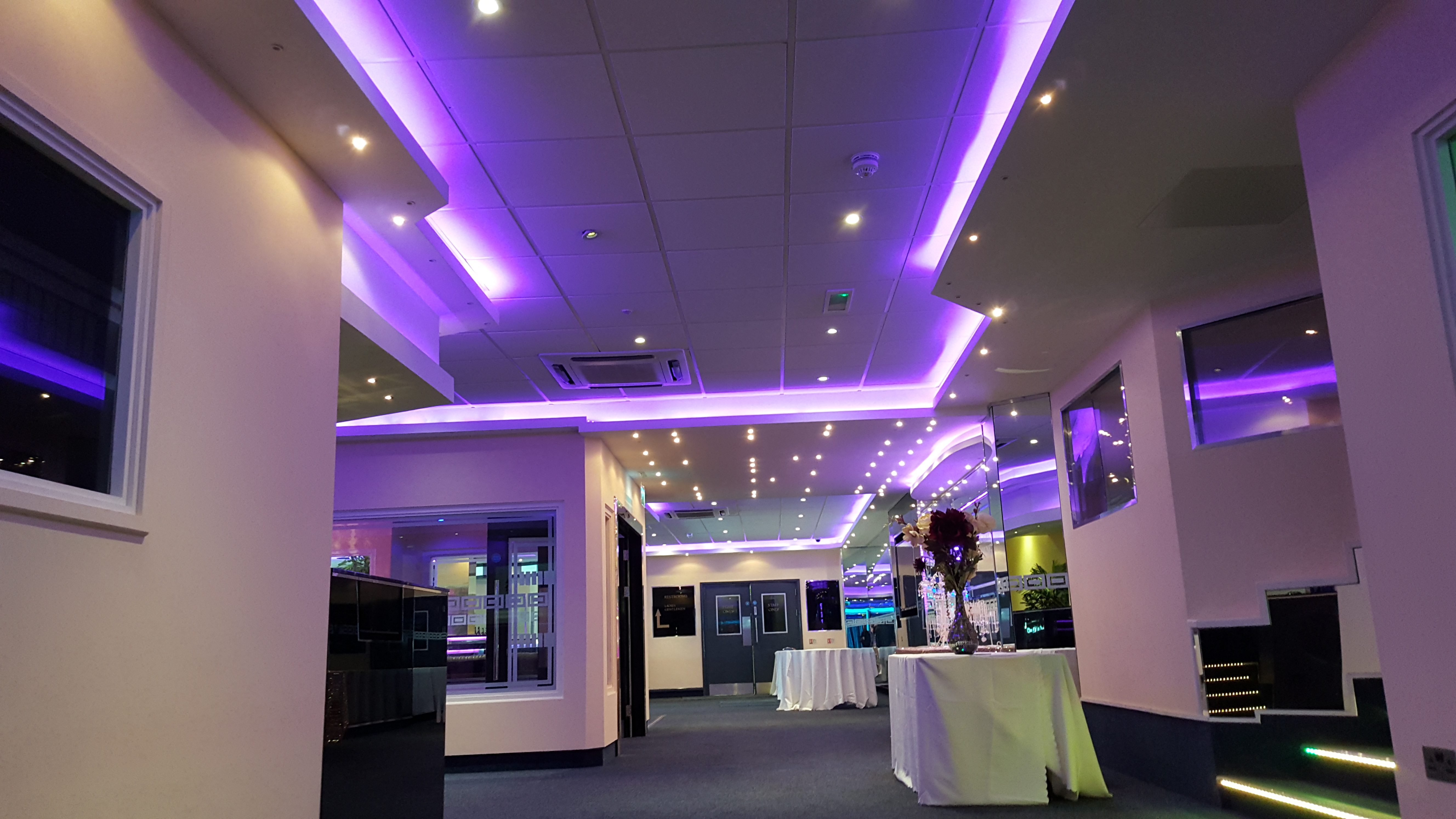 Modern executive lounge with vibrant purple lighting for corporate meetings and social events.