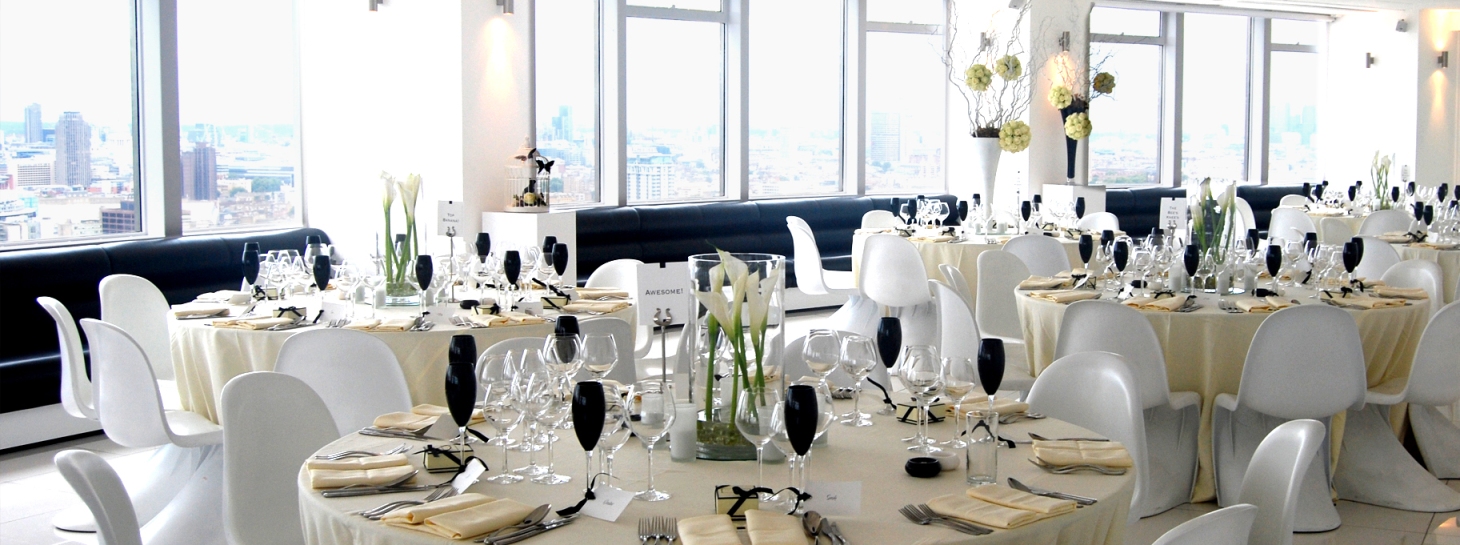 Elegant event space at Altitude 360, featuring round tables and white floral centerpieces. - Banner