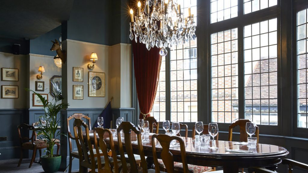 Elegant meeting space with wooden table, chandelier for corporate events. - Banner