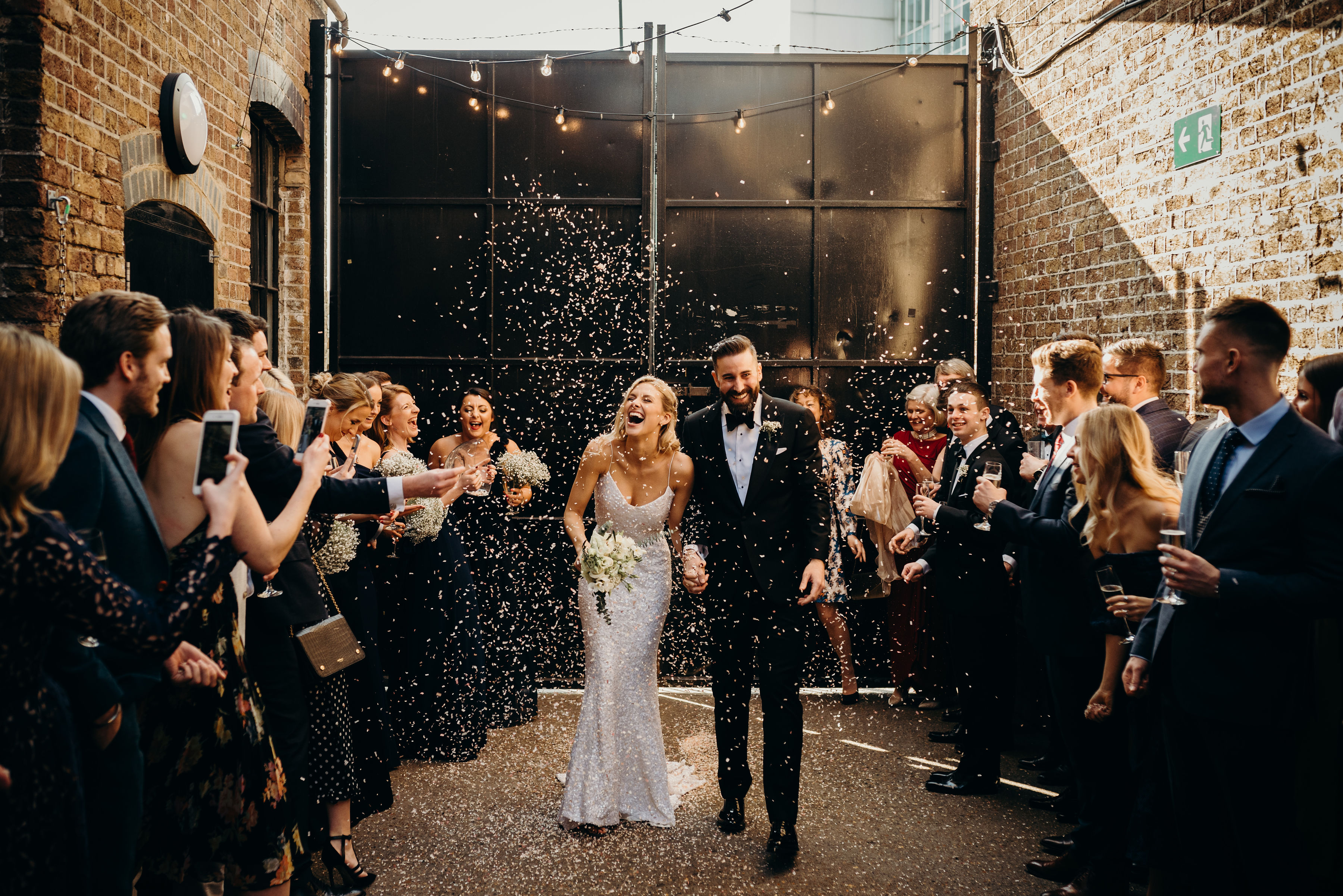 Joyful couple exiting wedding venue with confetti in Daylight Courtyard, Loft Studios. - Banner
