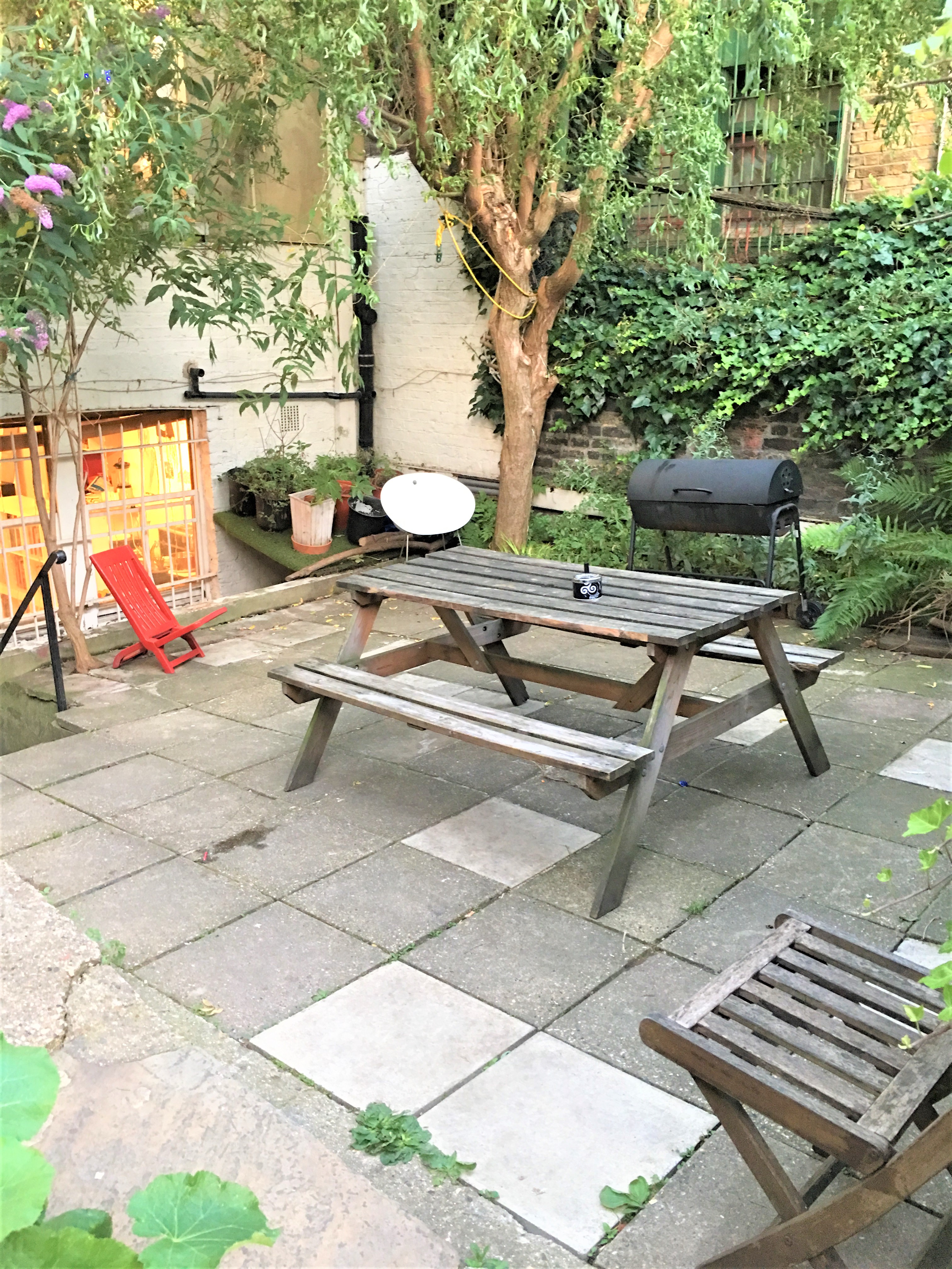 Cozy outdoor venue in Dalston Den with picnic table and grill for casual events.