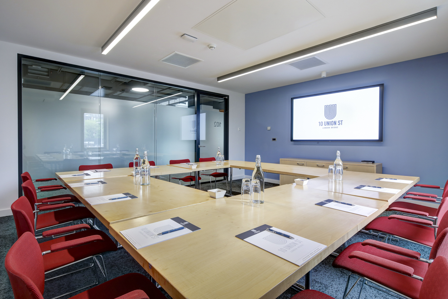 Modern meeting room with large table and red chairs for collaborative events.