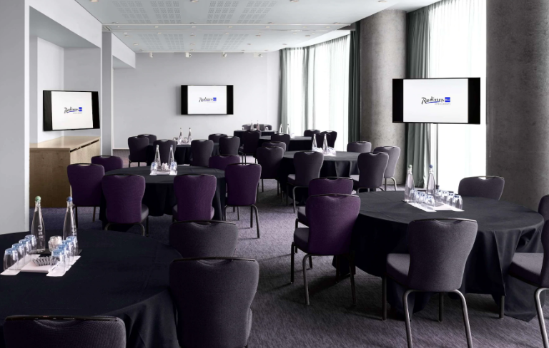 Modern meeting space in Radisson Blu Birmingham with round tables for corporate events.
