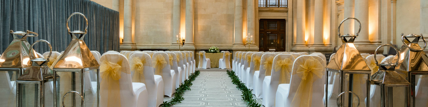 Elegant wedding ceremony space with gold-sashed chairs and floral decor in Bristol Harbour Hotel.