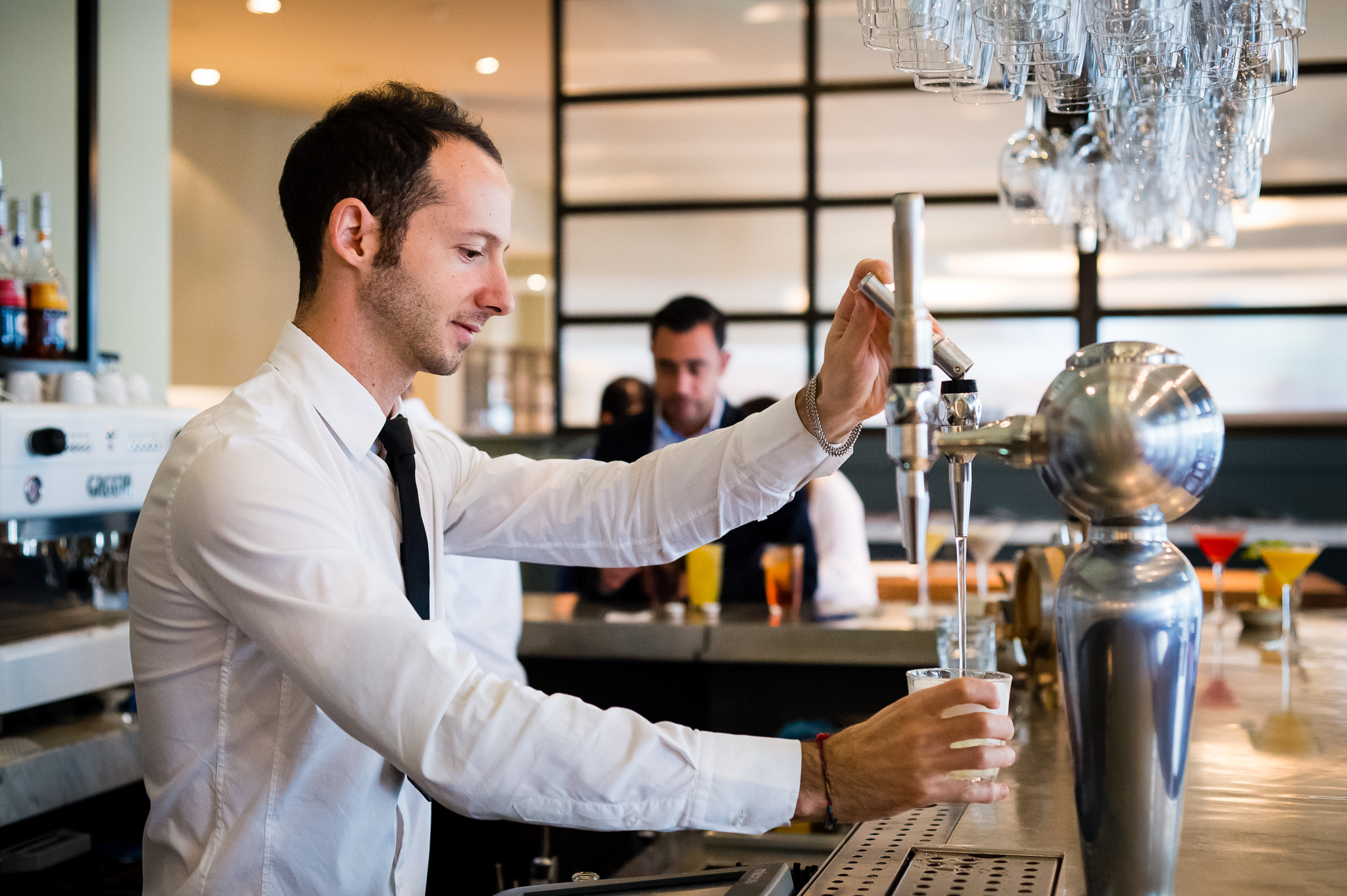 Bartender pouring drink at TOZI Restaurant & Bar, perfect for networking events. - Banner