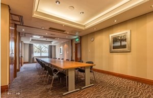 Meeting room in Thistle Kensington Gardens with wooden table, ideal for corporate events.