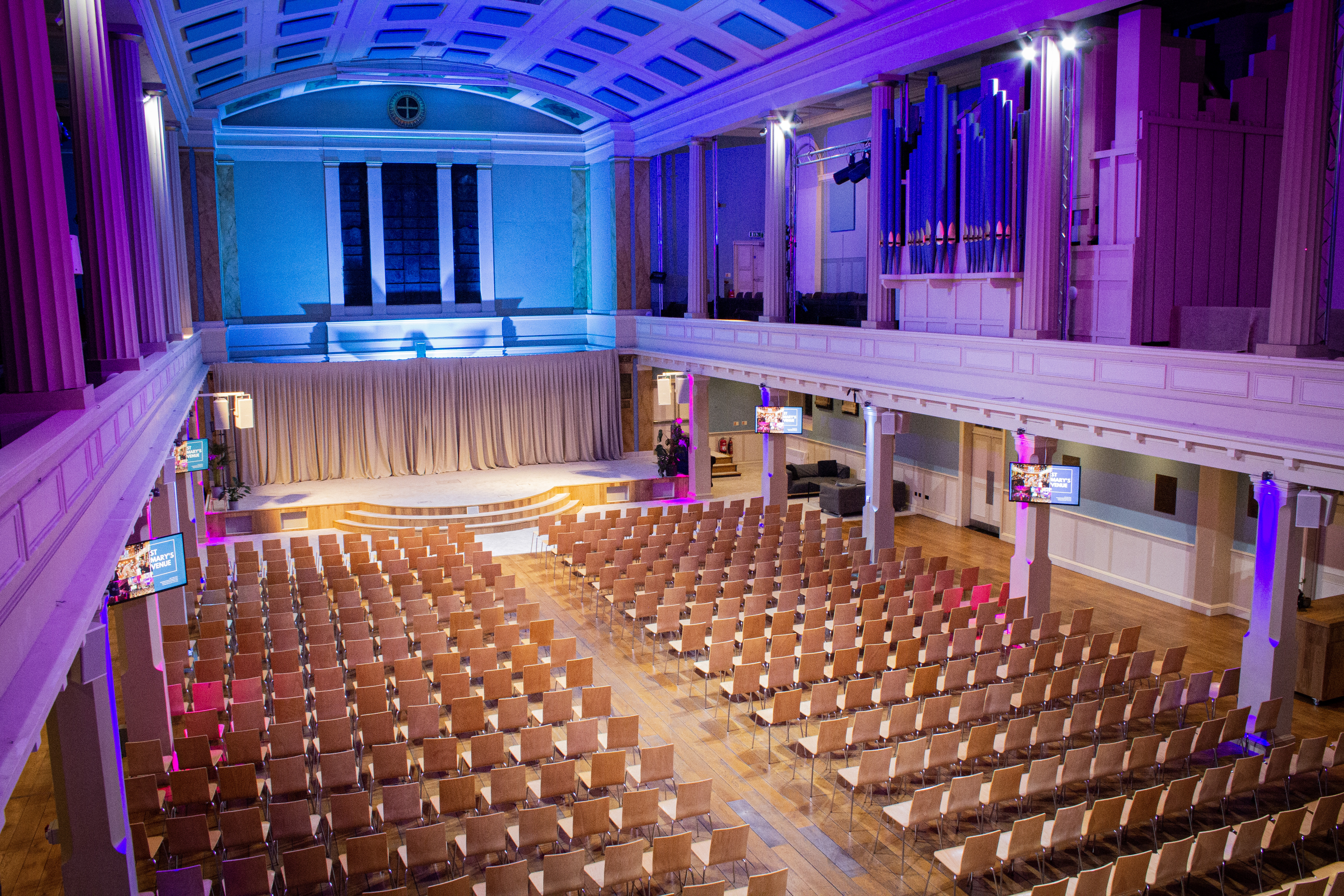 Spacious St Mary's Marylebone venue set for conferences with vibrant lighting and seating. - Banner