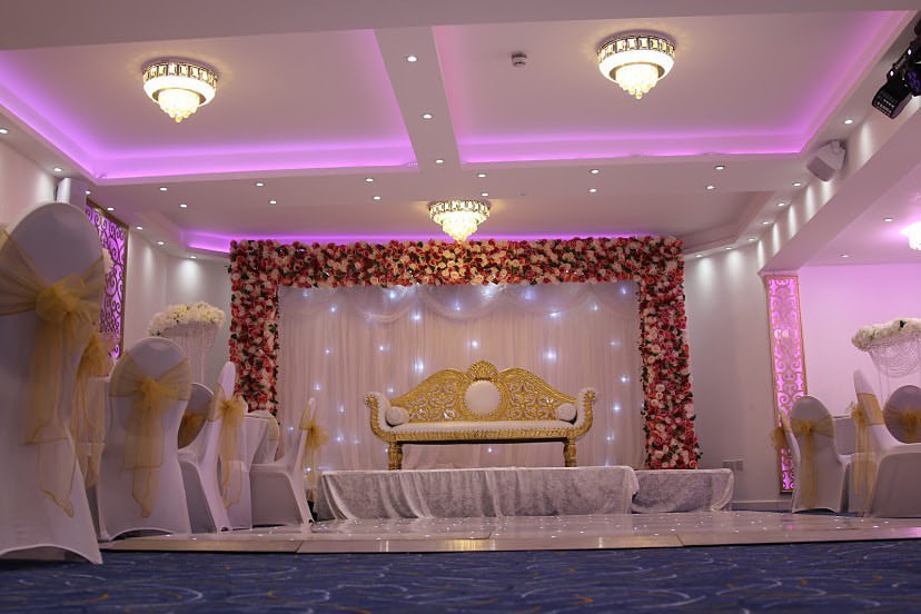 Elegant wedding venue with white chairs and floral backdrop at Oscaar Banqueting. - Banner