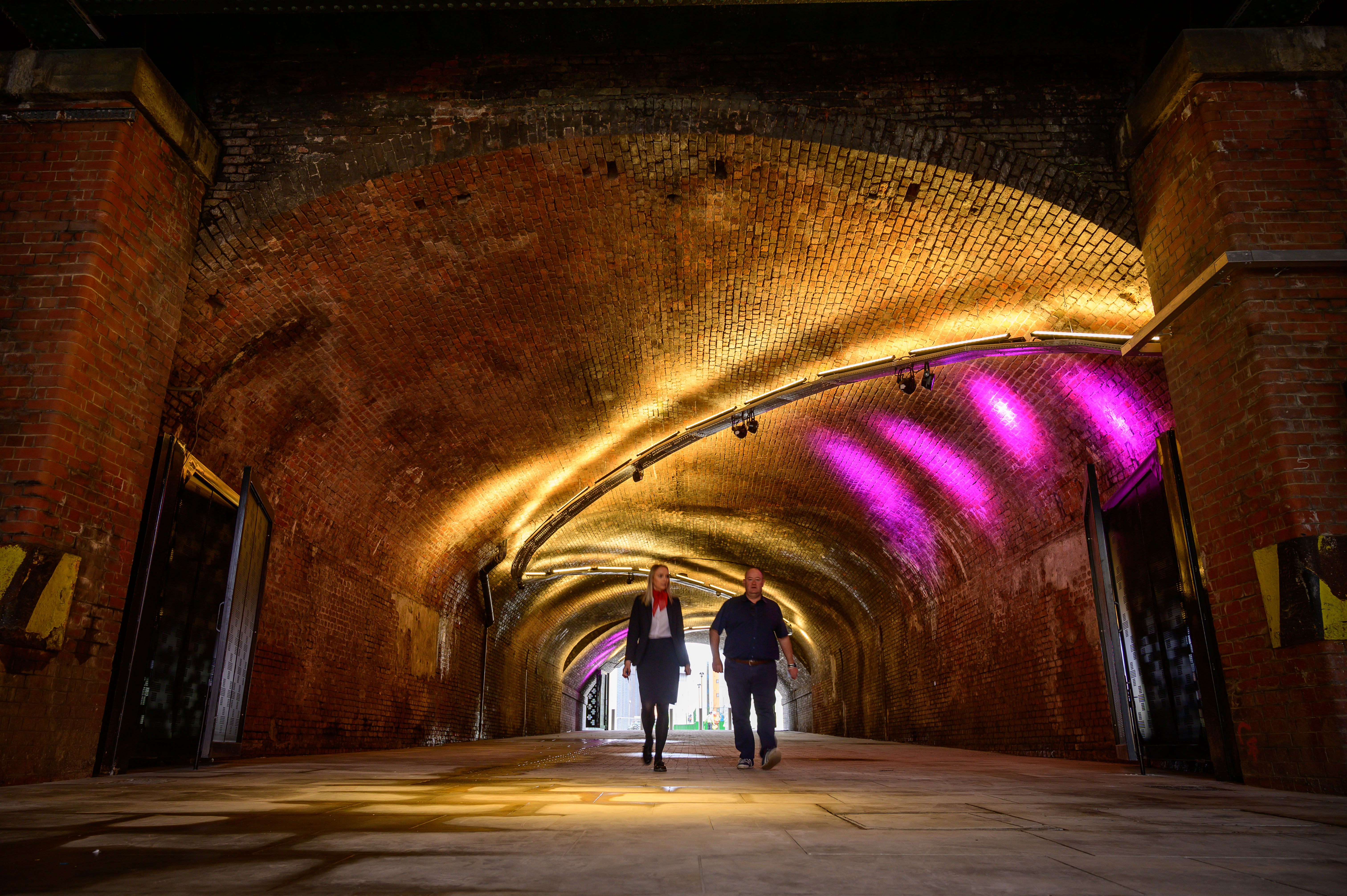 The Arch event space with arched brick tunnel and vibrant purple lighting for receptions. - Banner