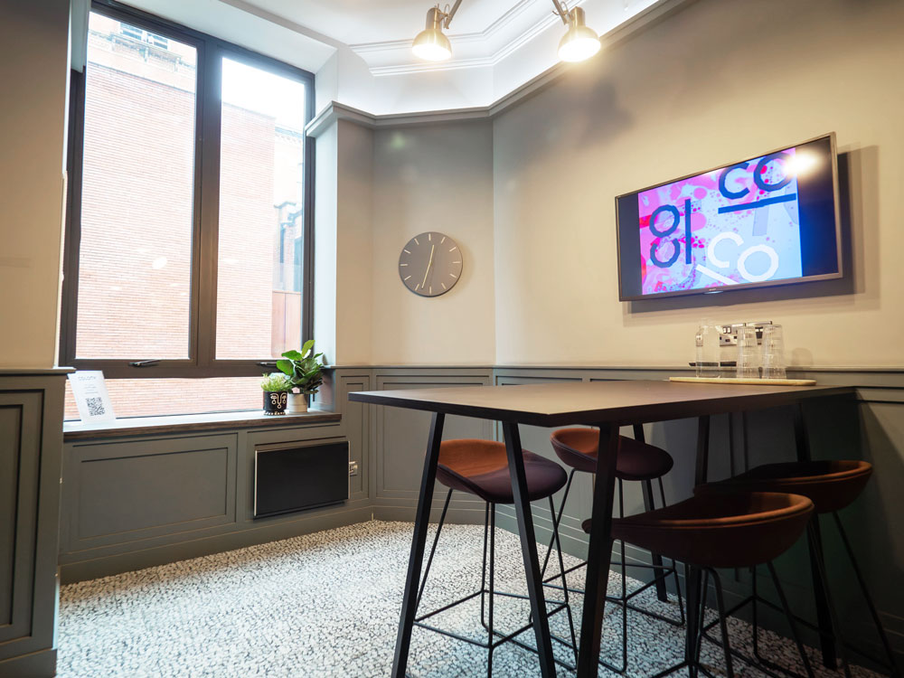 Modern meeting room with high table, natural light, ideal for collaboration and brainstorming.