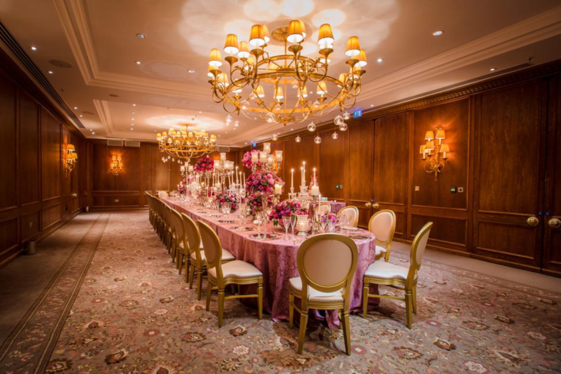 Elegant banquet room at Four Seasons London, featuring pink tablecloth and floral centerpieces. - Banner