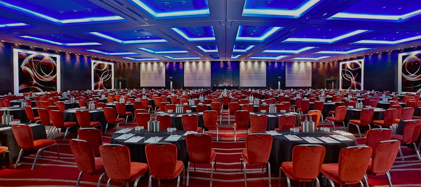 Westminster Ballroom setup for a conference with elegant lighting and red chairs. - Banner