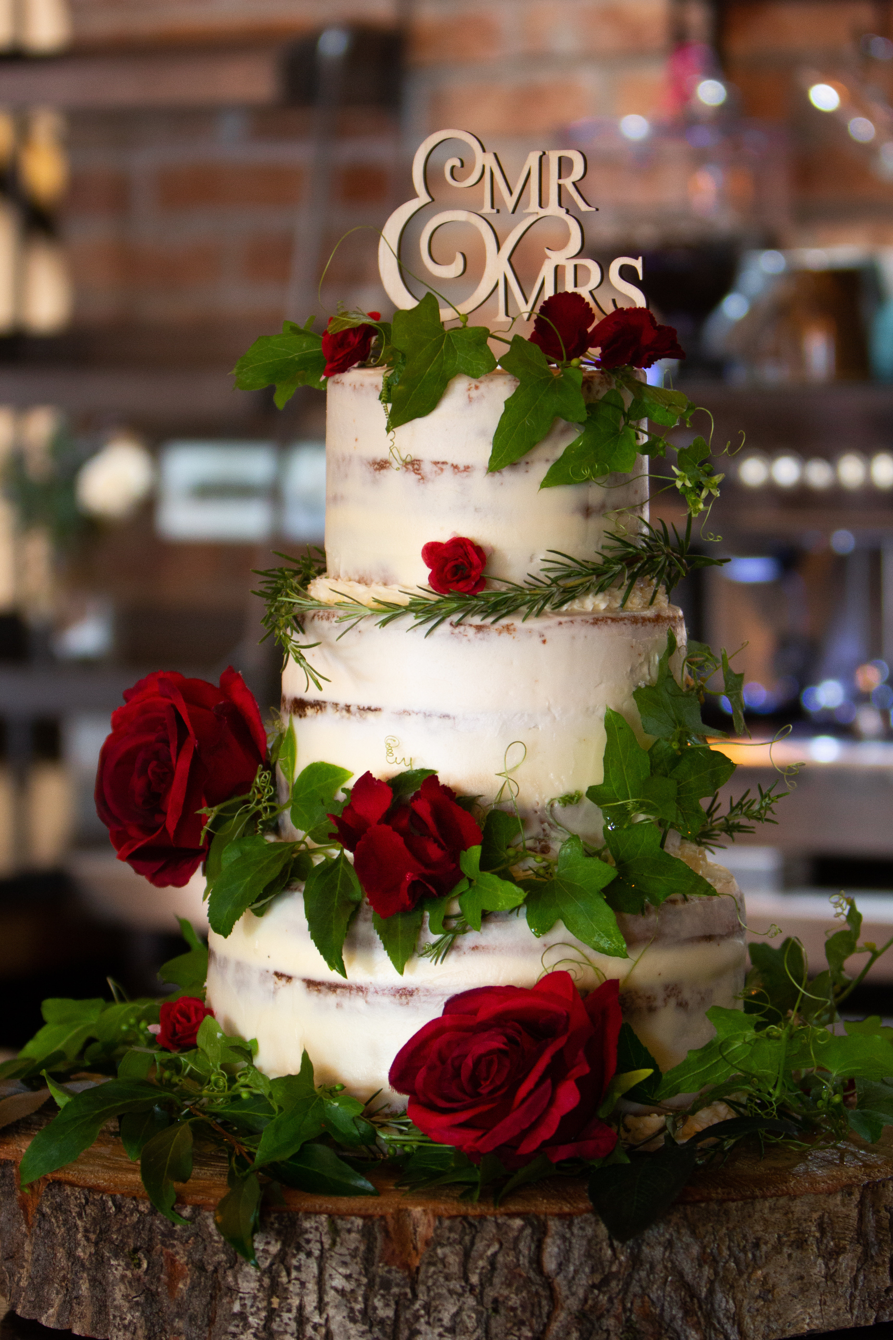 Three-tiered wedding cake with roses at Rising Cafe, perfect for romantic events. - Banner
