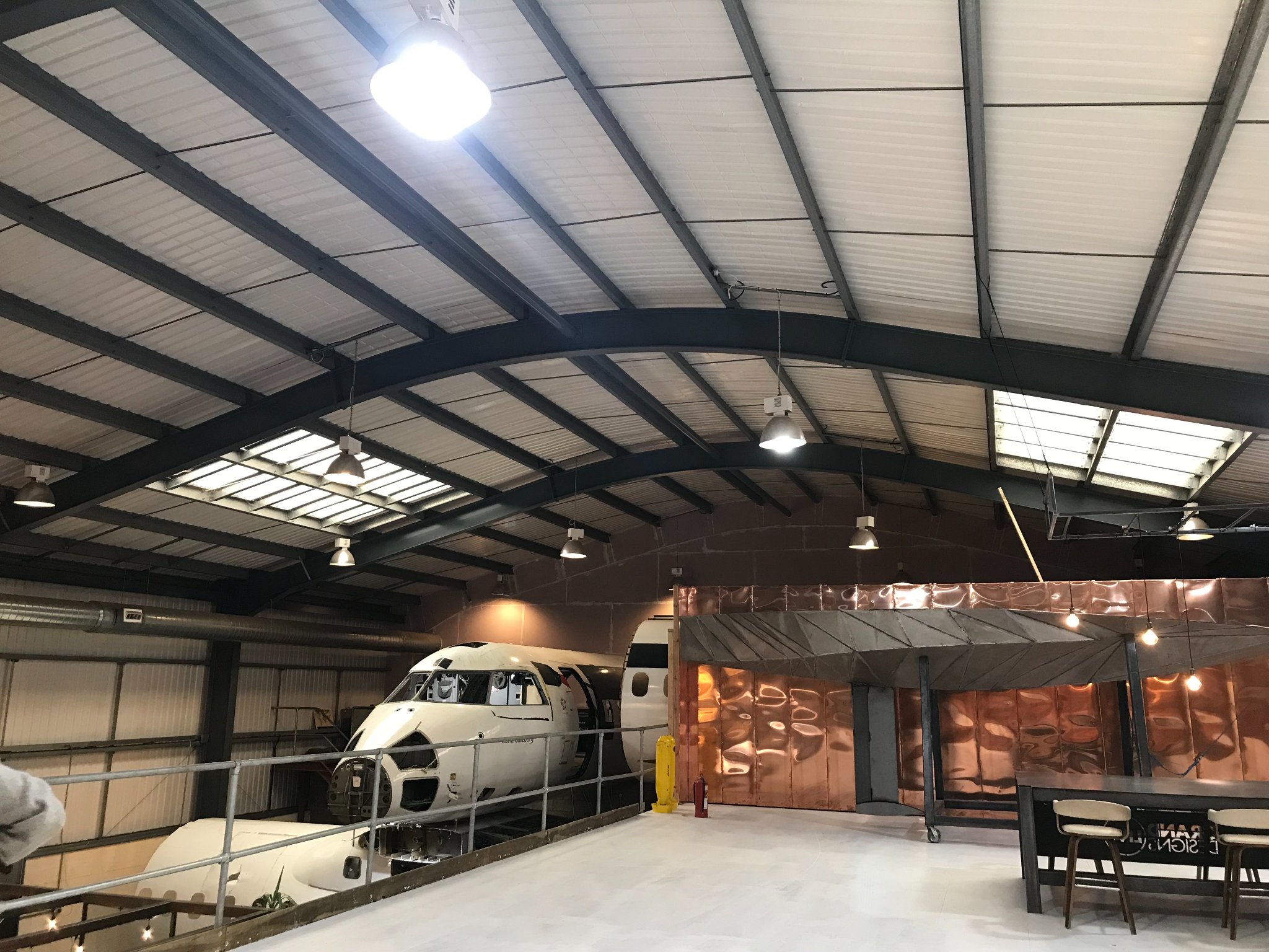 Aviation-themed event space with aircraft centerpiece, ideal for corporate gatherings. - Banner