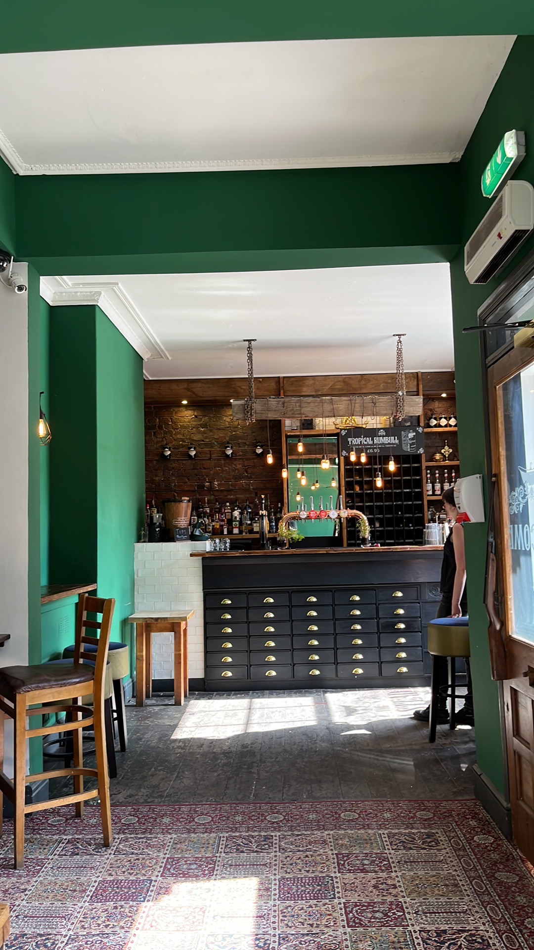 Stylish bar with rustic wood and green walls, perfect for networking events and gatherings.