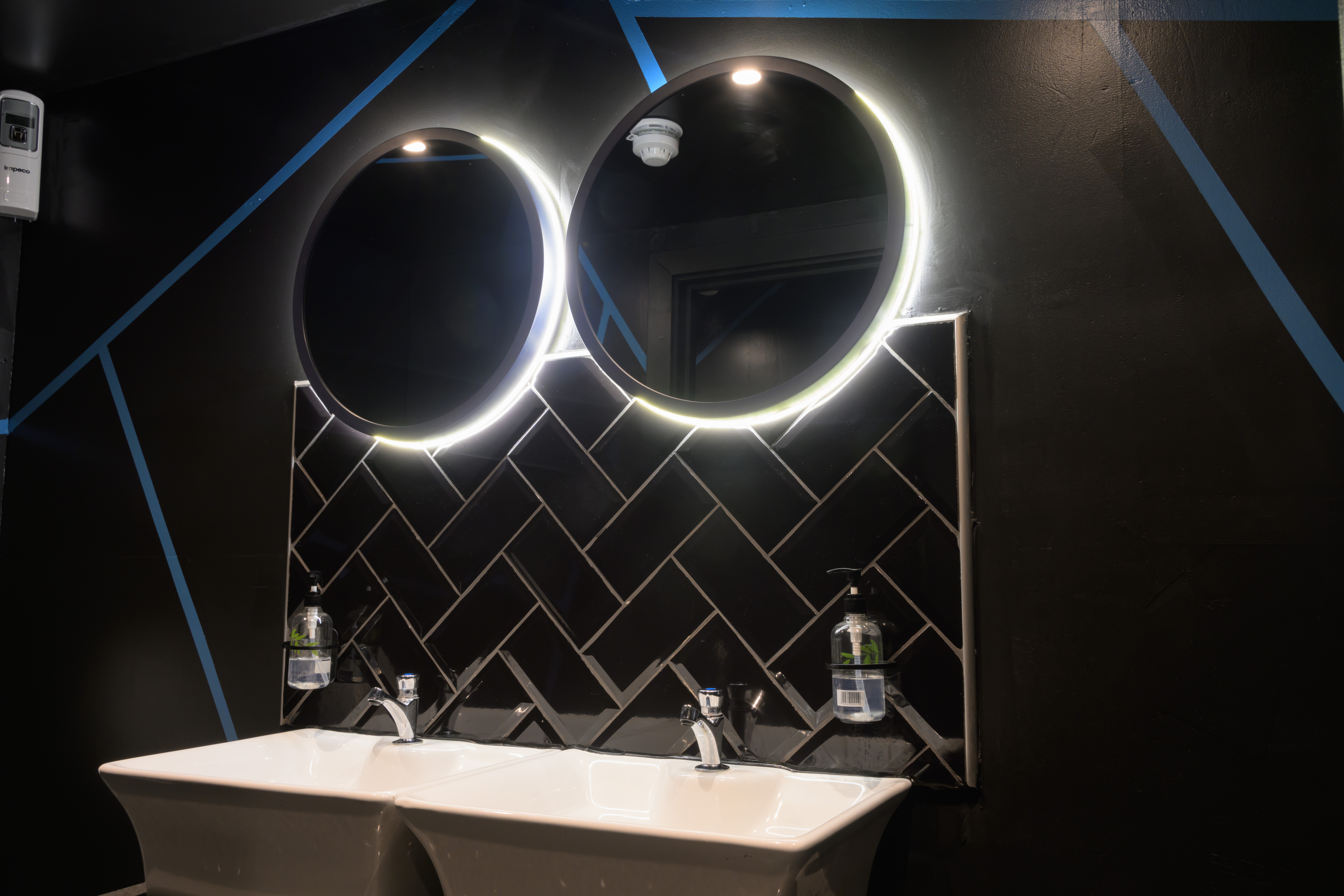 Modern restroom with illuminated mirrors and double sink at Alaska Waterloo venue.