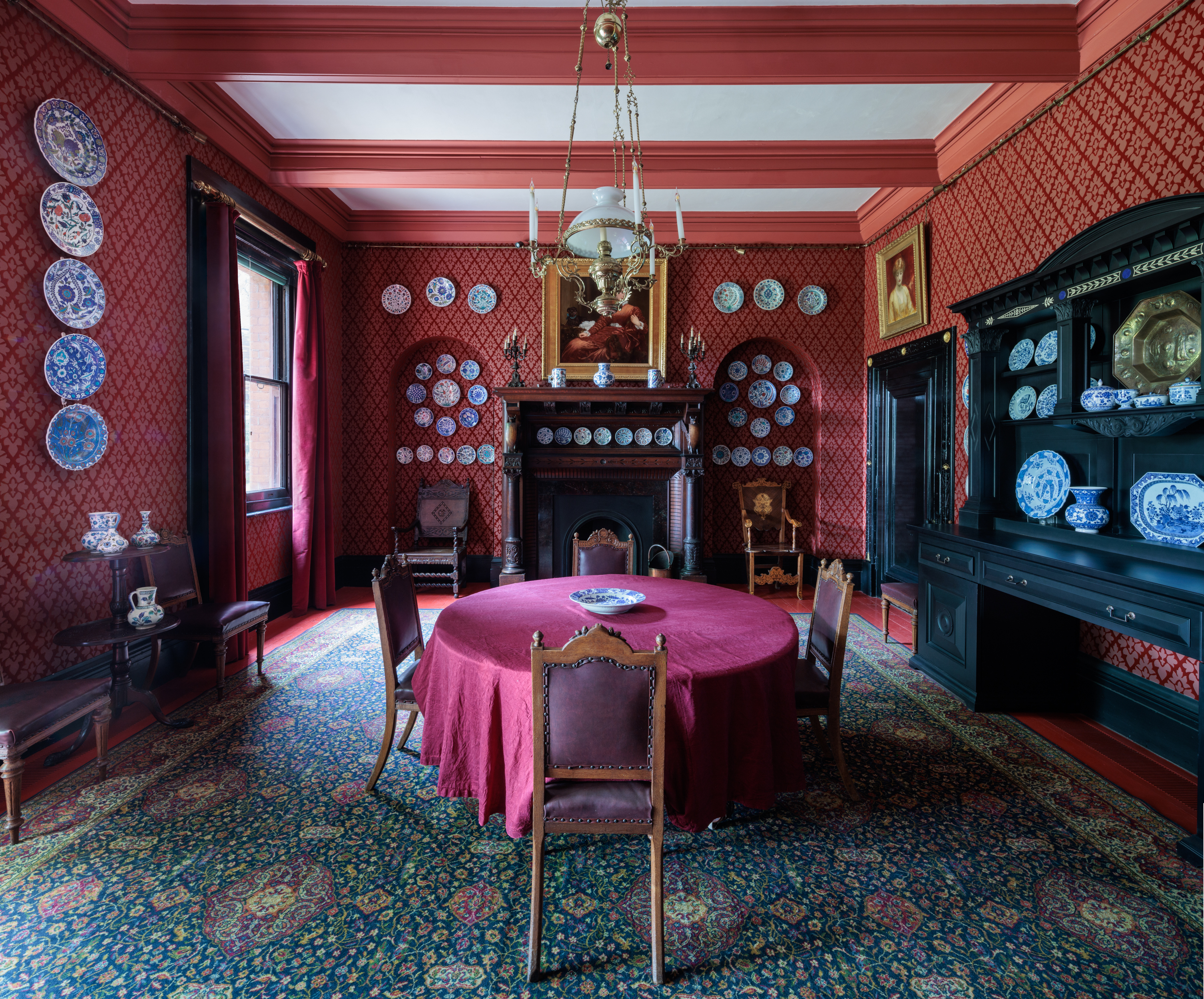 Elegant dining room in Leighton House with red wallpaper, ideal for executive meetings.