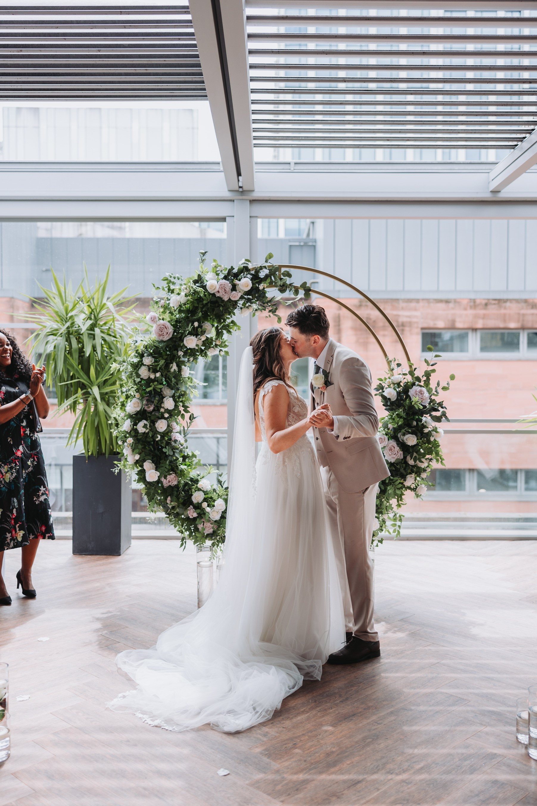 Wedding ceremony in Manchester Hall under a floral arch, showcasing elegant decor.