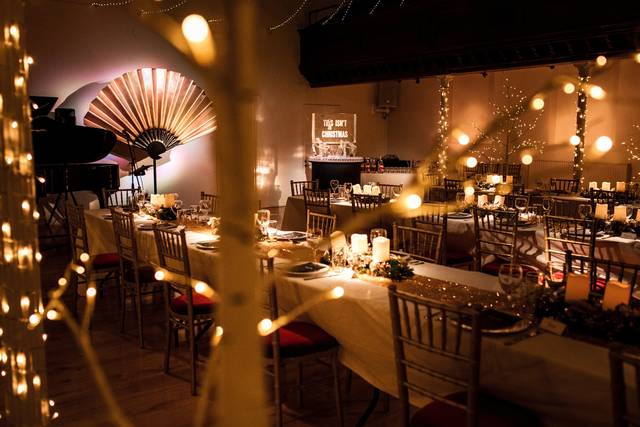Elegant event space with set tables and string lights for sophisticated dinners or celebrations. - Banner
