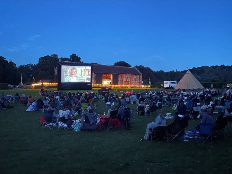 Outdoor movie screening with large screen in a wedding marquee setting.